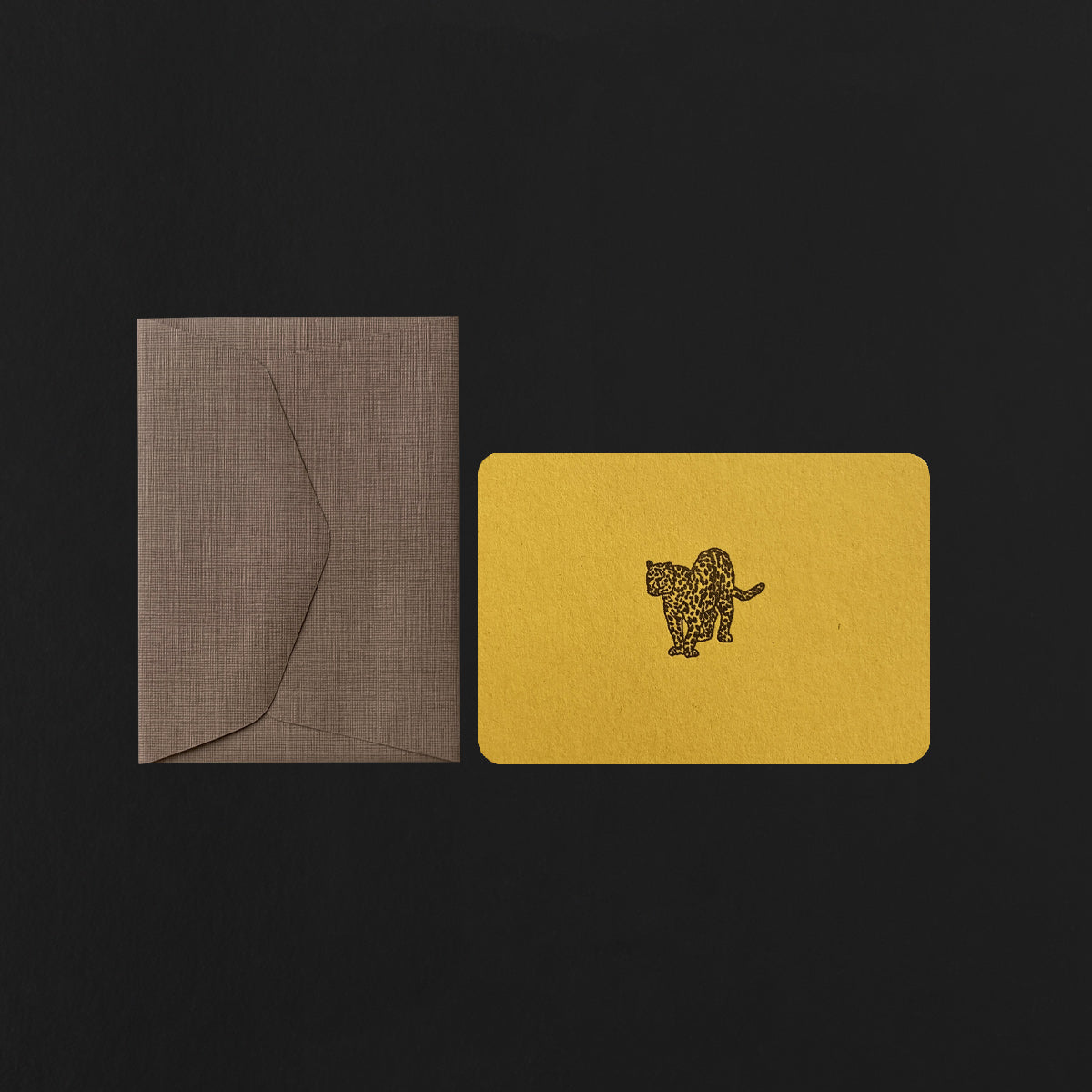 Yellow card with a cheetah design and brown envelope on a black background