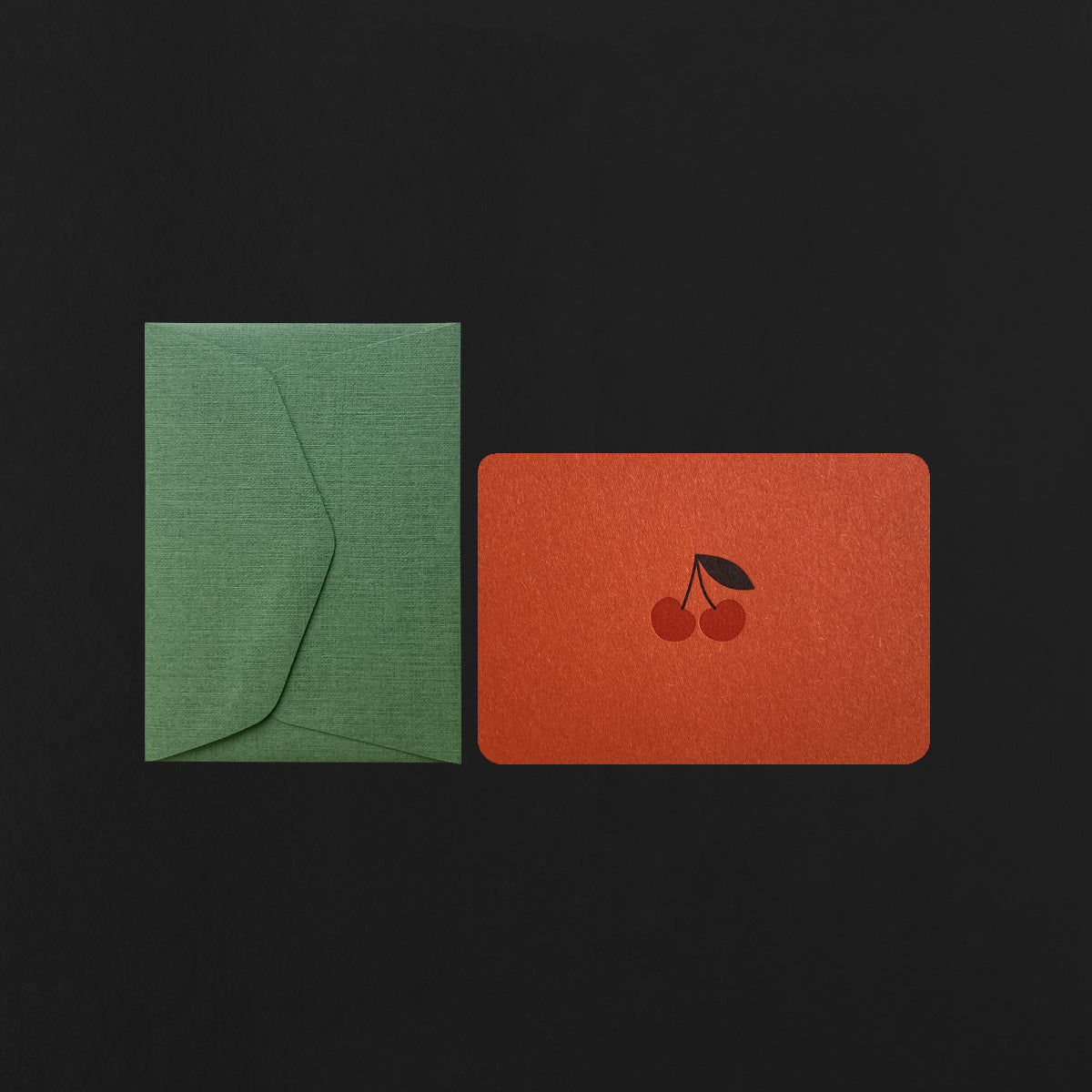 Green envelope and red card with a cherry design on a black background
