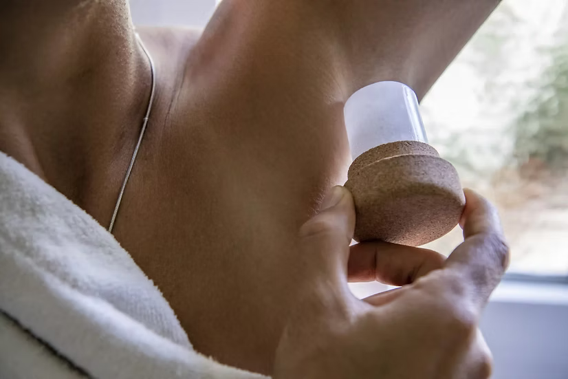 Person putting on the Biork natural deodorant with a blurred background