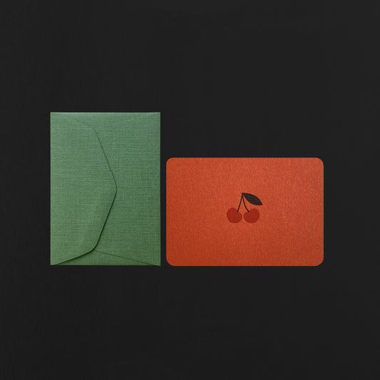 Green envelope and red card with a cherry design on a black background