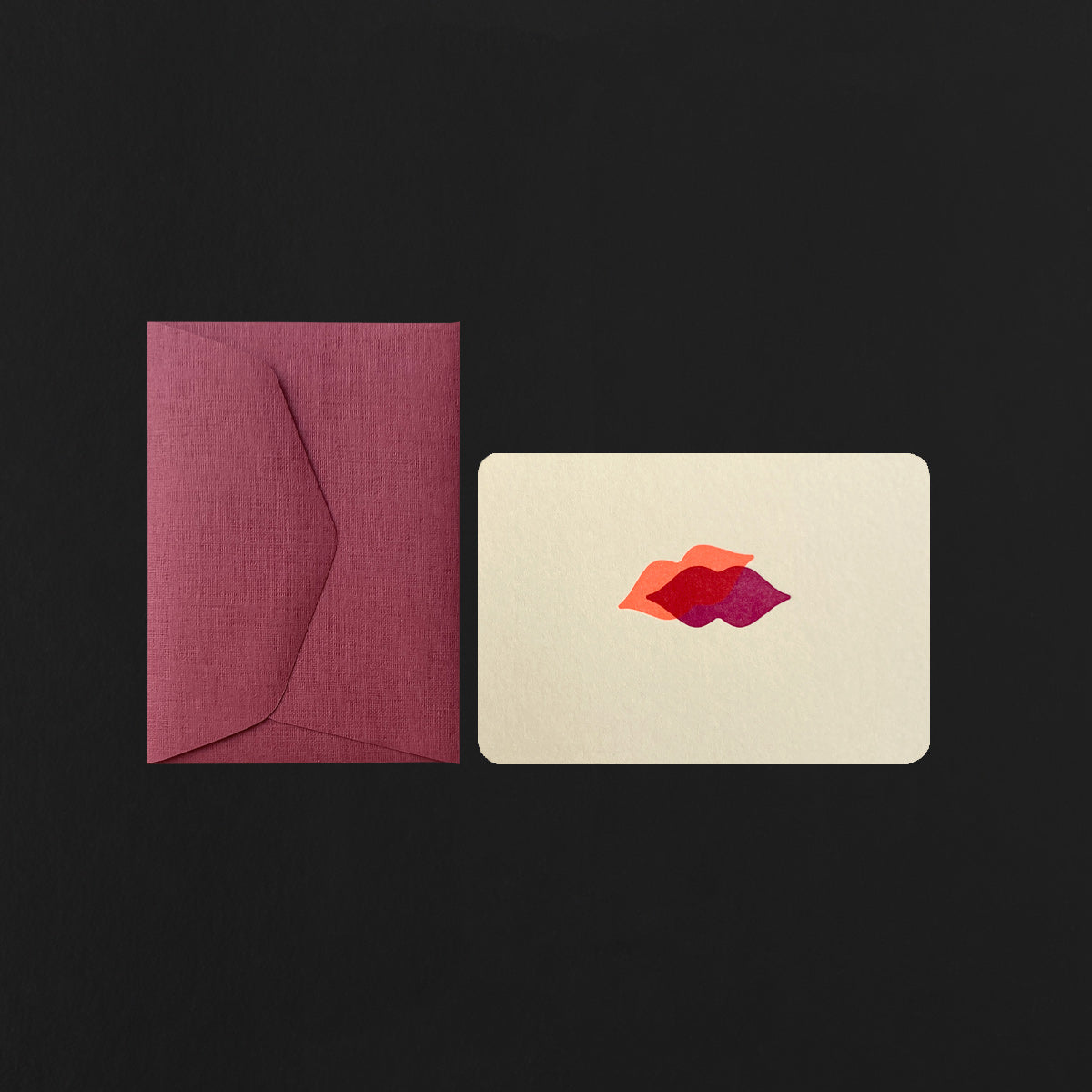 beige card with a 2 mouths design and wine red envelope on a black background