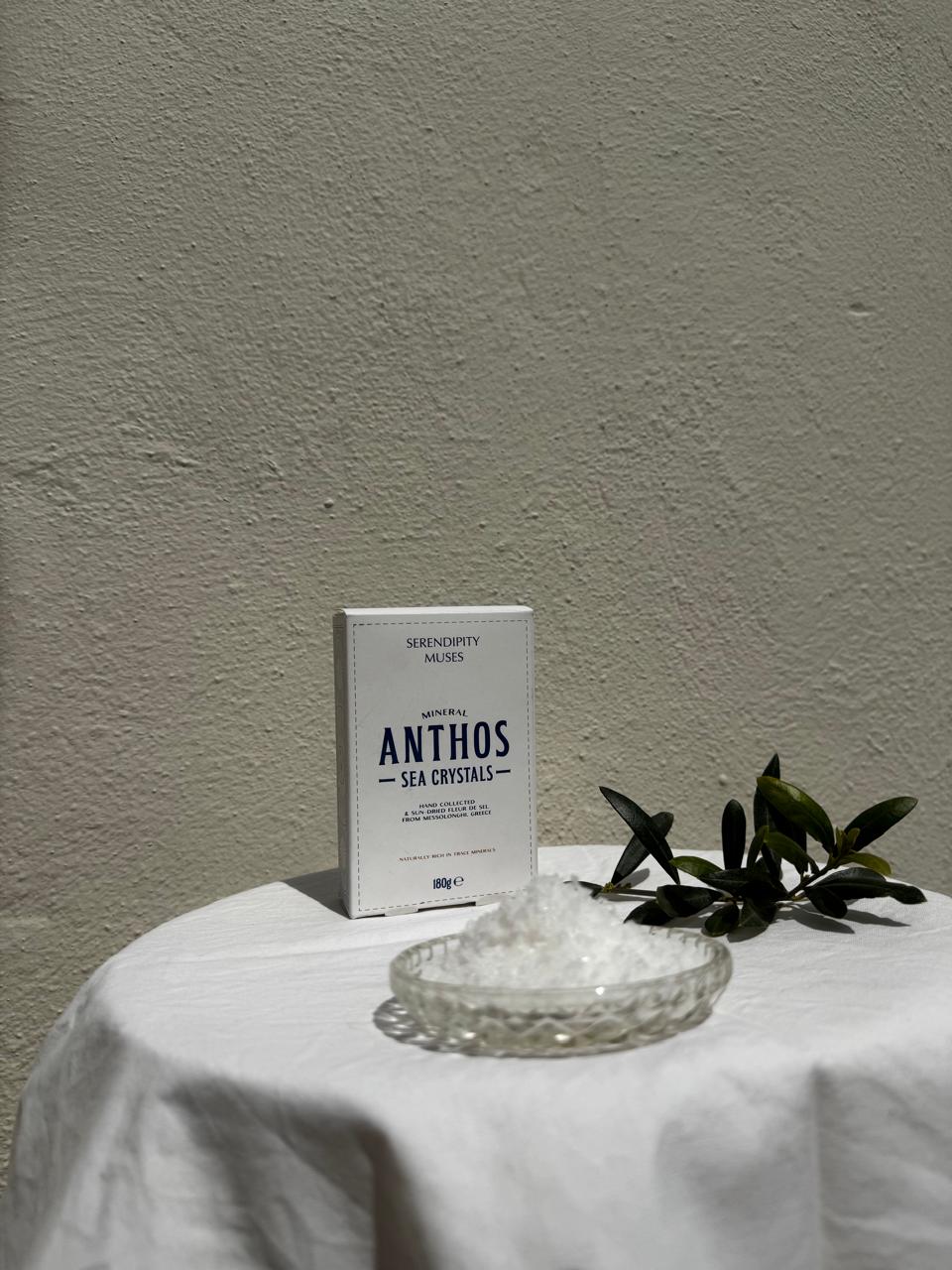 Product packaging labeled 'ANTHOS Mineral Sea Crystals' on a white surface with a plant in the background.