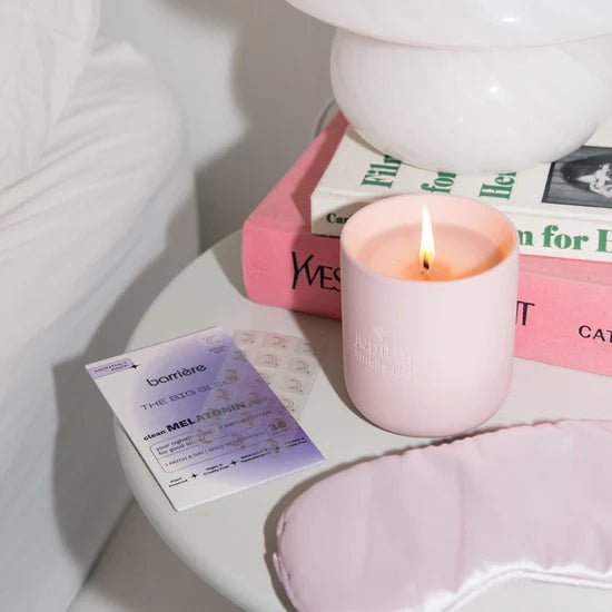 Barriere melatonin patches packaging with gold moon symbols on a nightstand next to burning candle