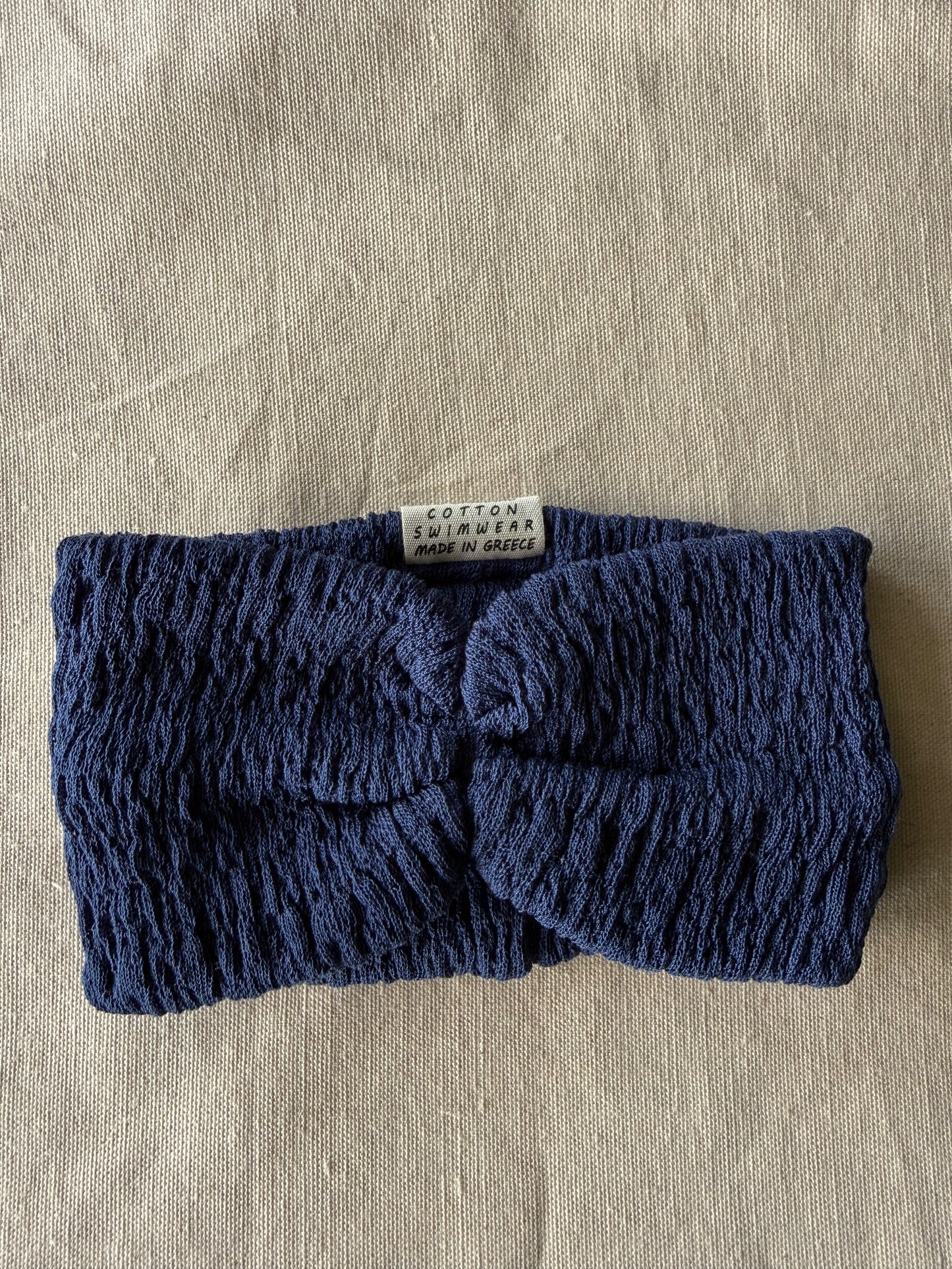 Blue knitted headband on a beige fabric background