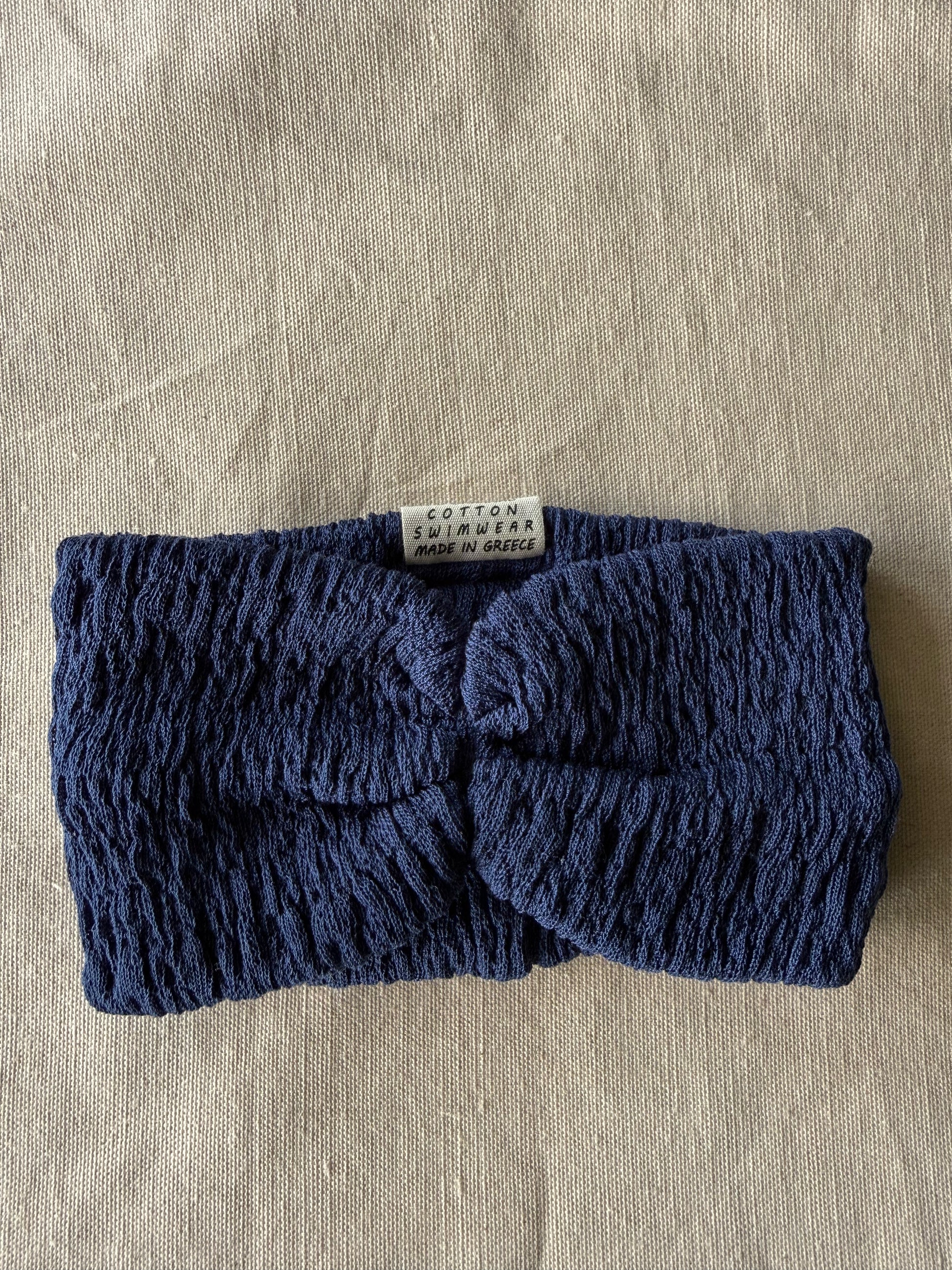 Blue knitted headband on a beige fabric background