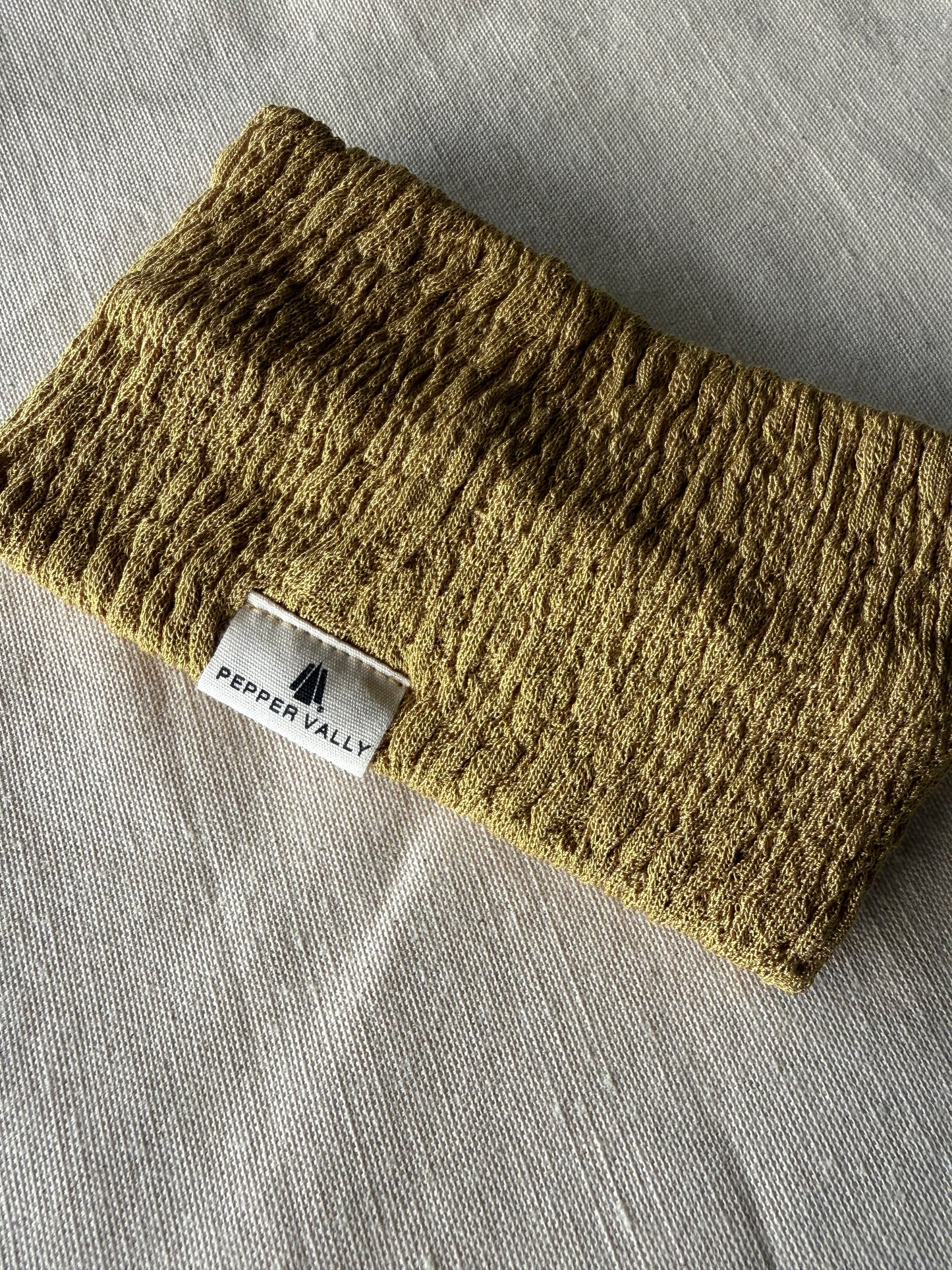 Knitted green headband with a visible brand label on a gray fabric background