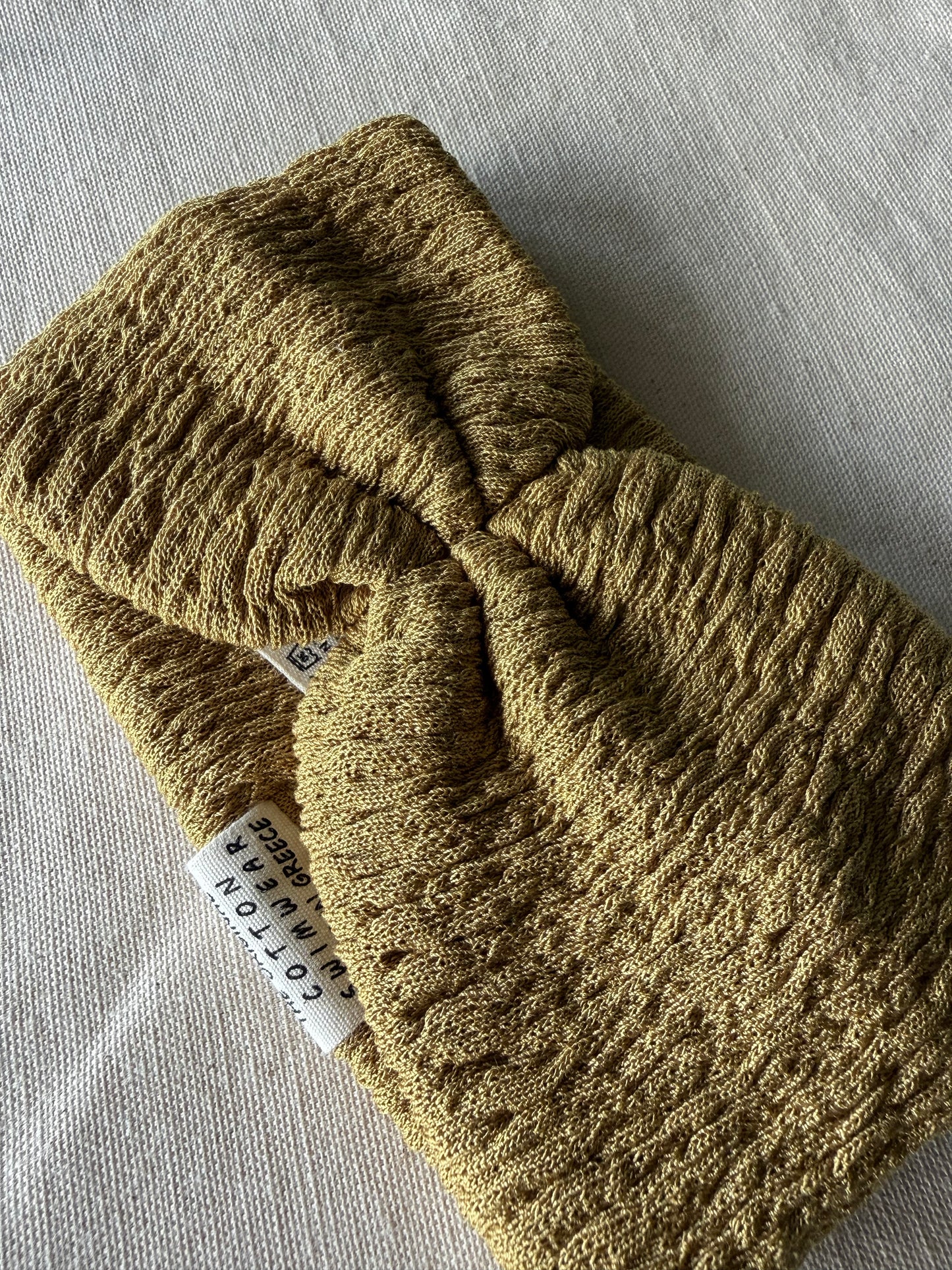Knitted green headband with a visible brand label on a gray fabric background