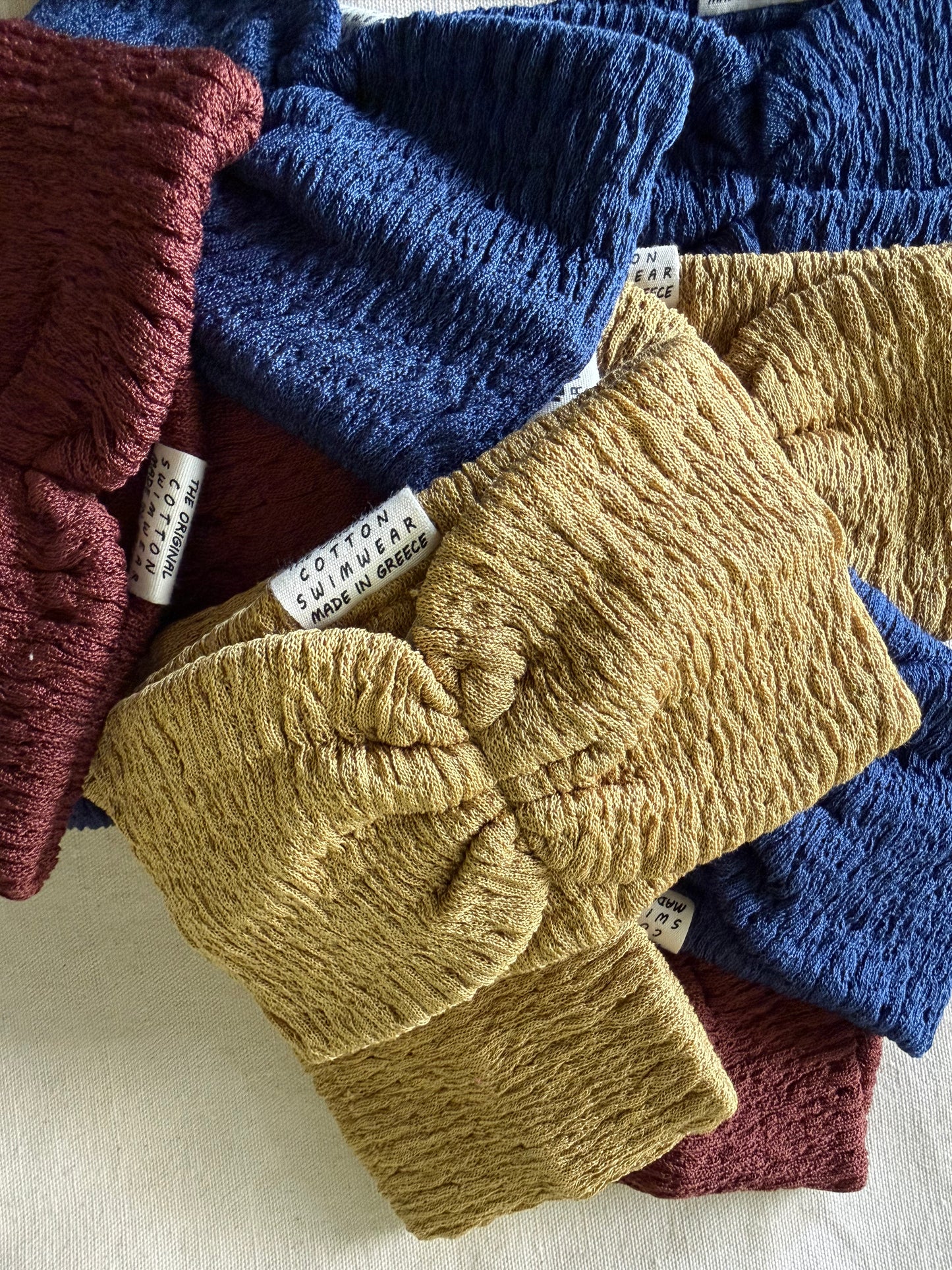 Stack of knitted headbands in blue, yellow, and red on a beige fabric background