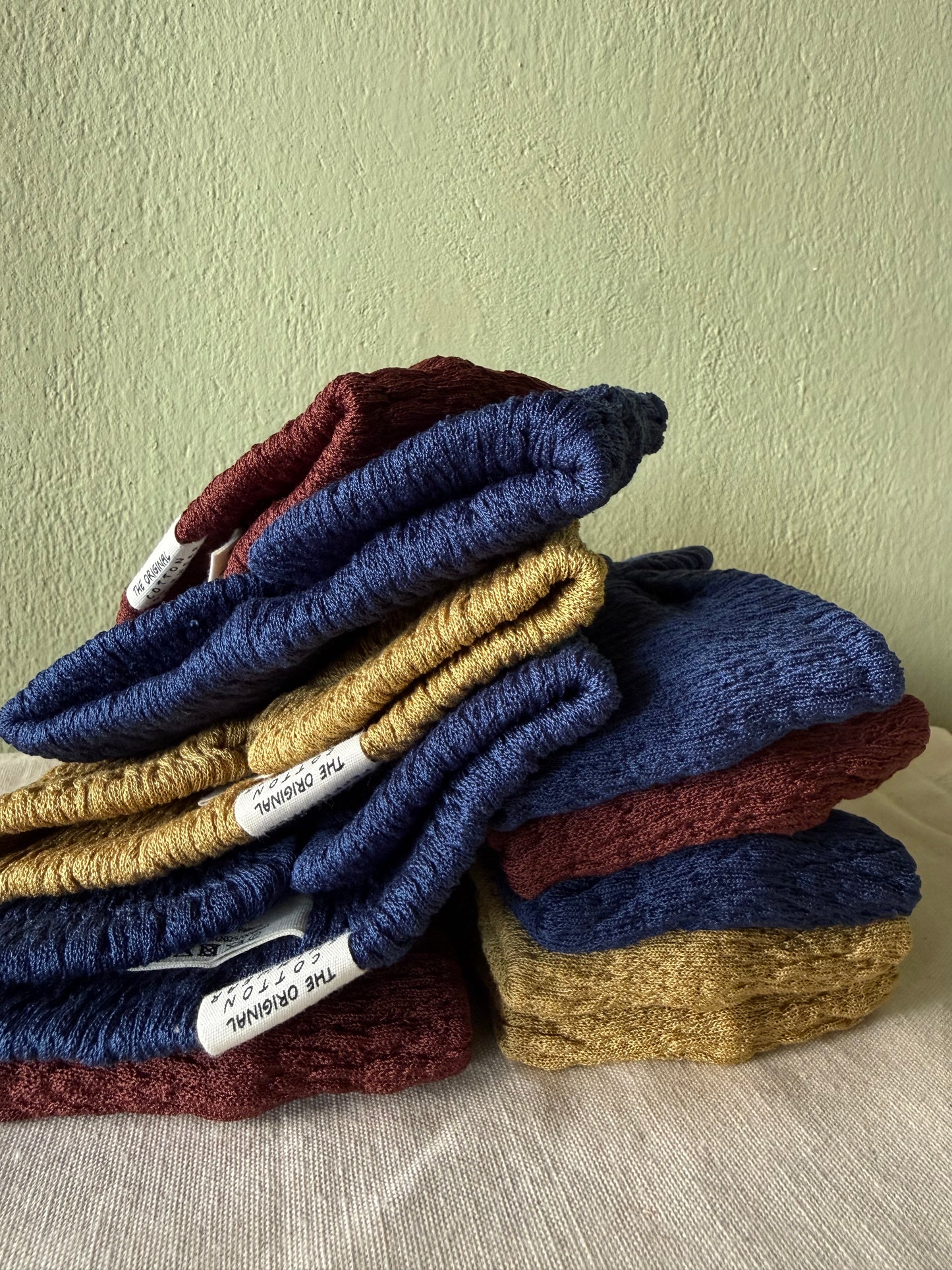Stack of knitted headbands in blue, yellow, and red on a neutral background