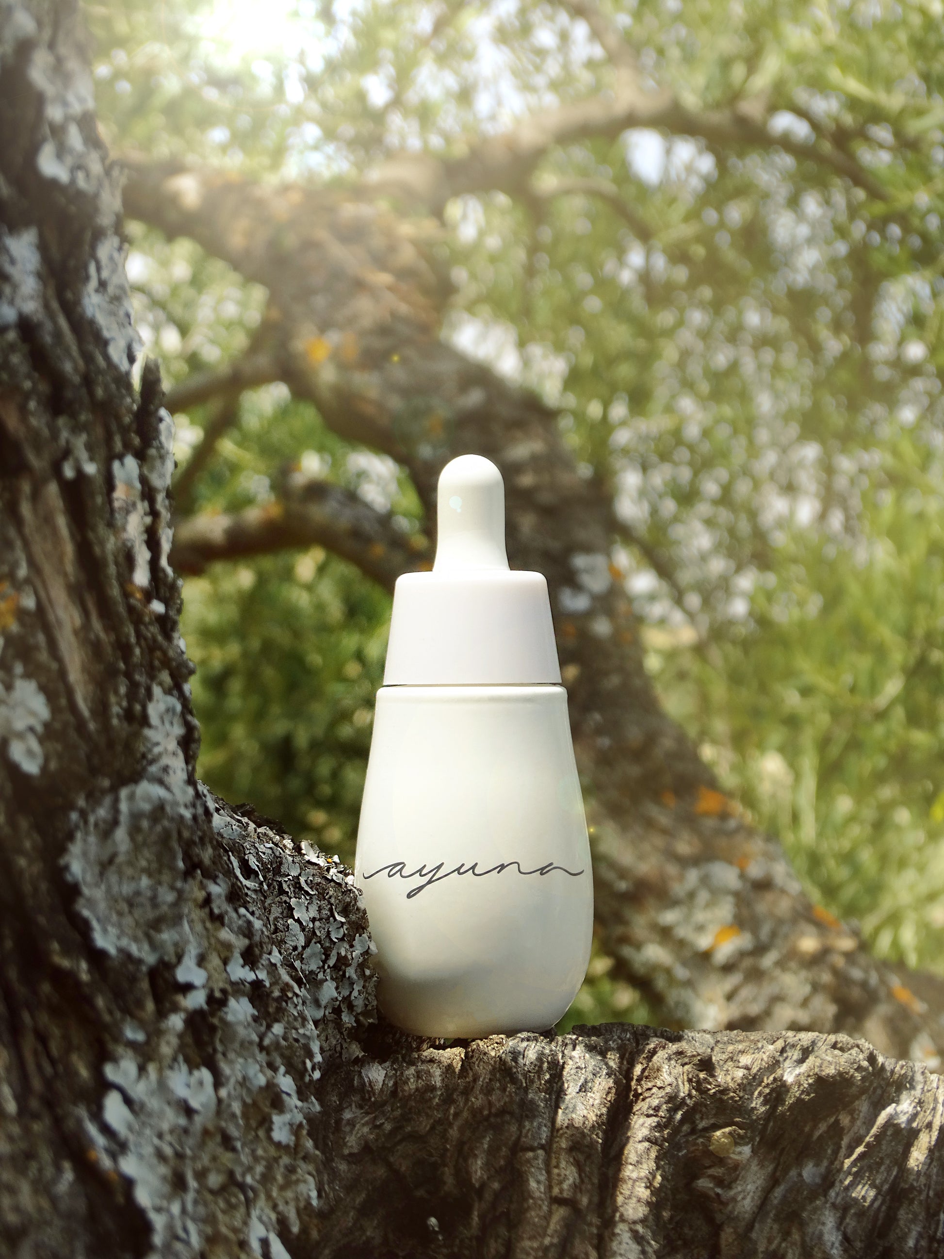 a white bottle of the ayuna cellular oil in nature
