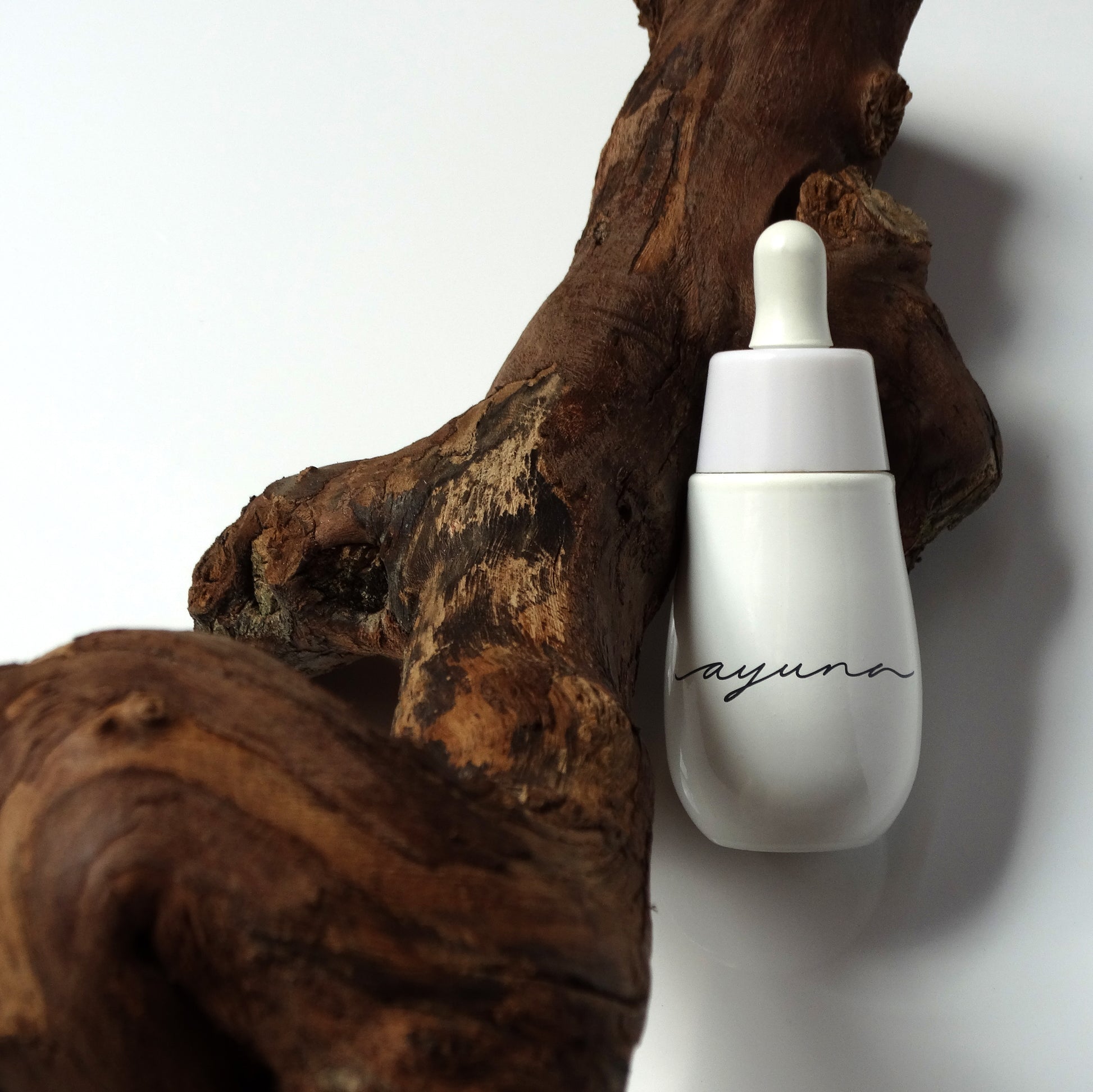 a white bottle of the ayuna cellular oil next to wood