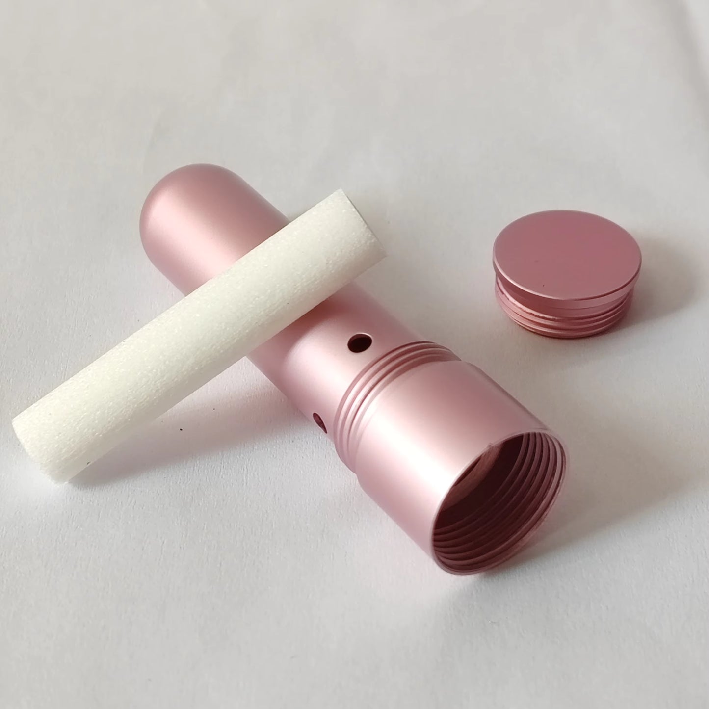 Pink cylindrical nasal inhaler with white cotton on a light gray background