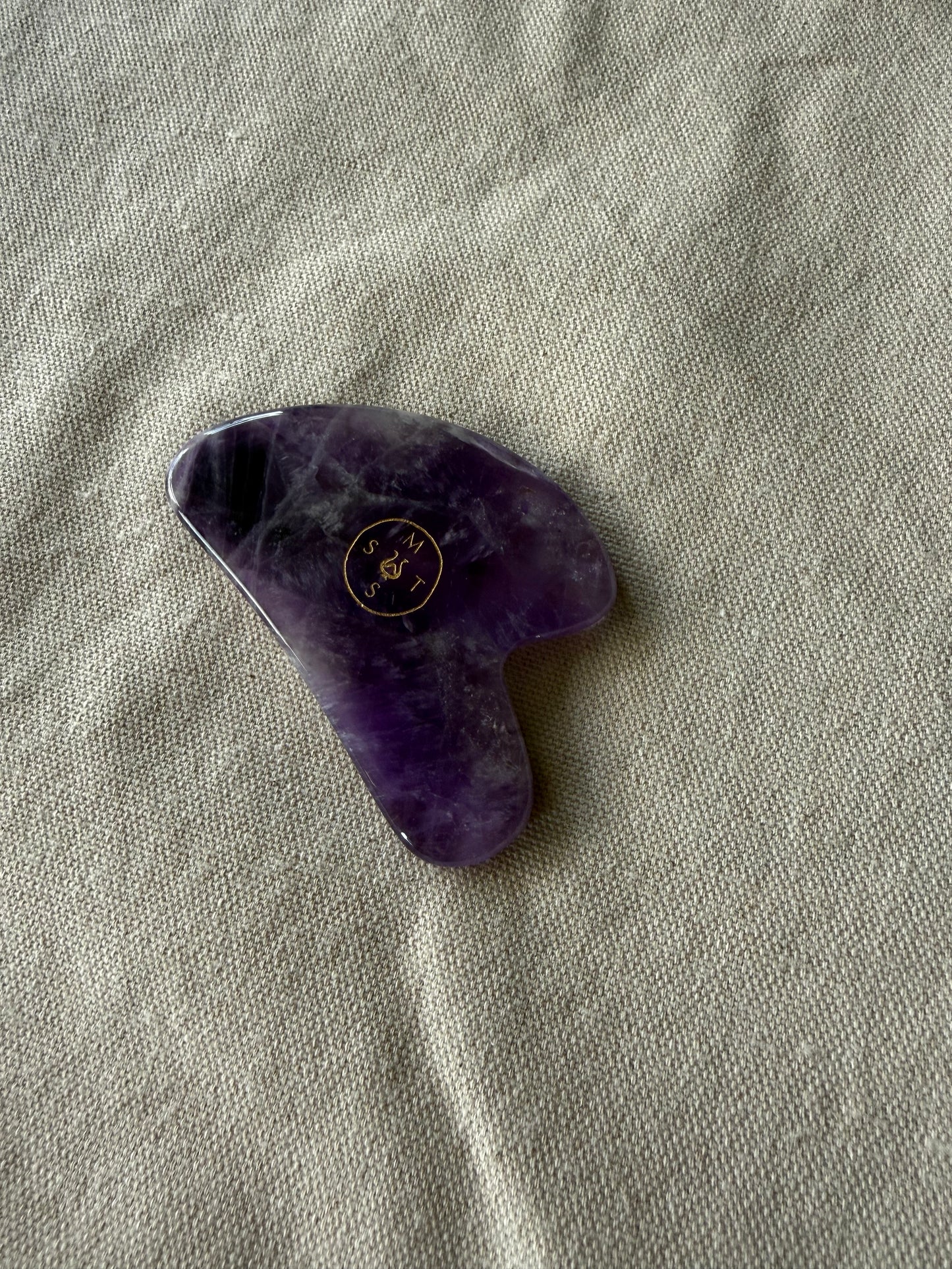     Natural amethyst gua sha stone with sculpted edges for facial massage, tension release, and glow support