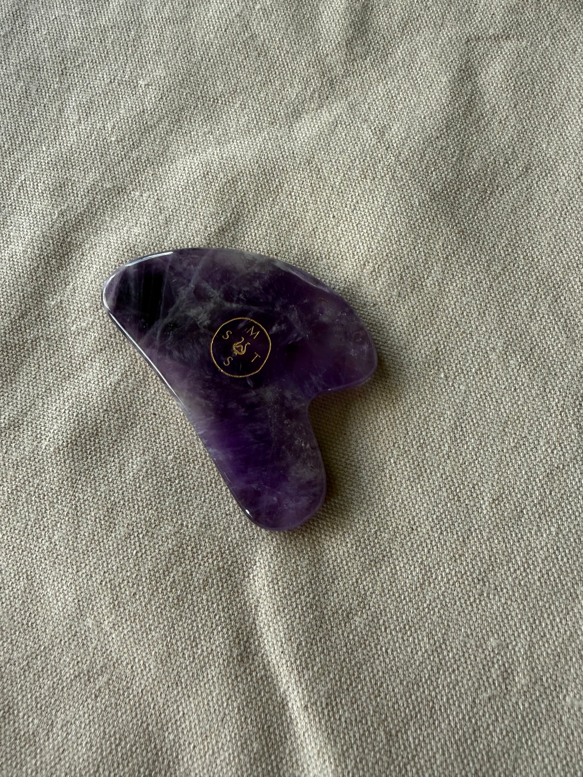     Natural amethyst gua sha stone with sculpted edges for facial massage, tension release, and glow support