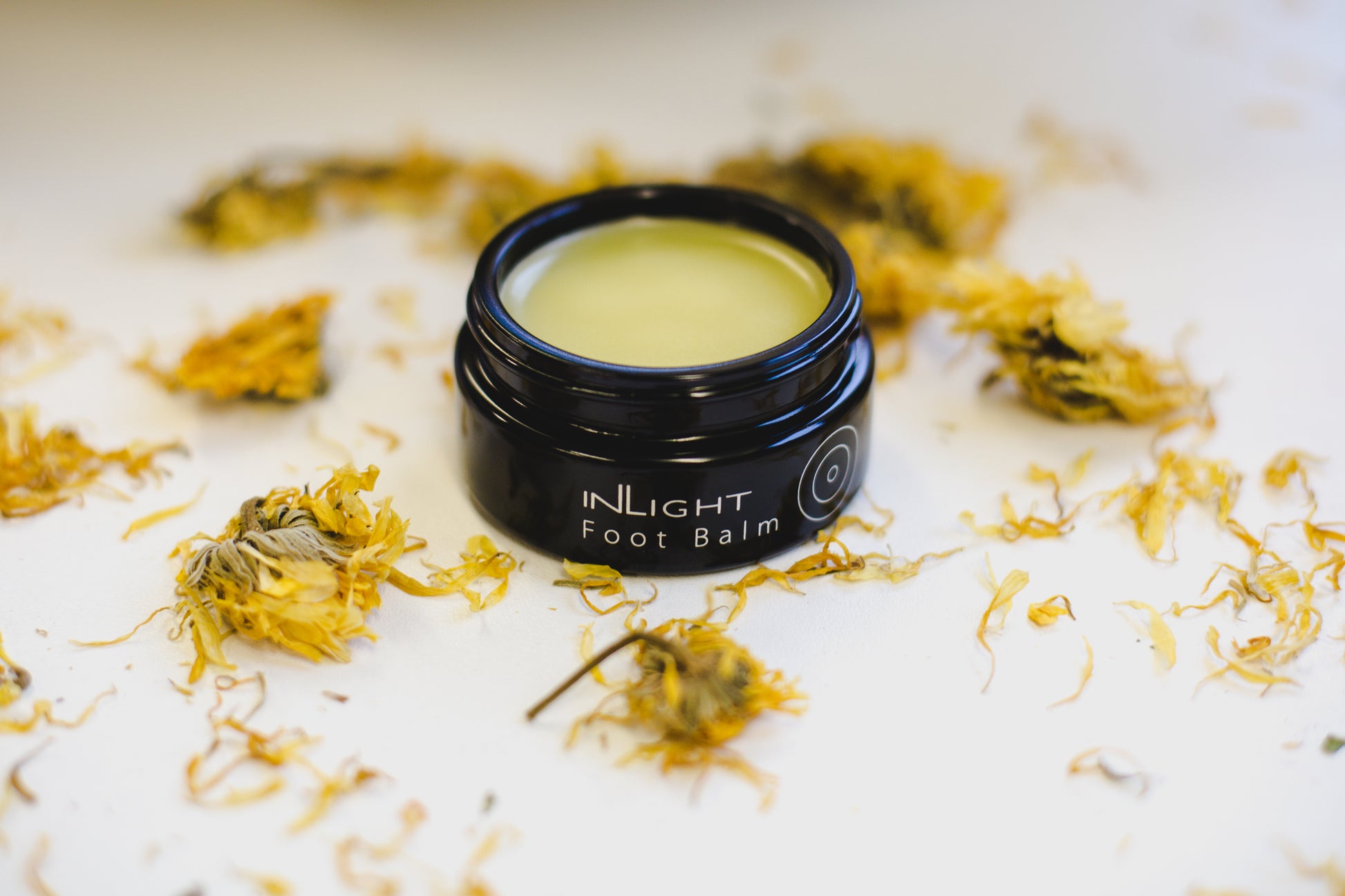 A jar of Inlight Foot Balm among calendula