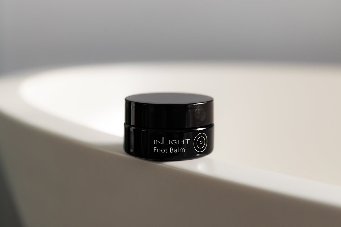 A jar of Inlight Foot Balm on a bathtub