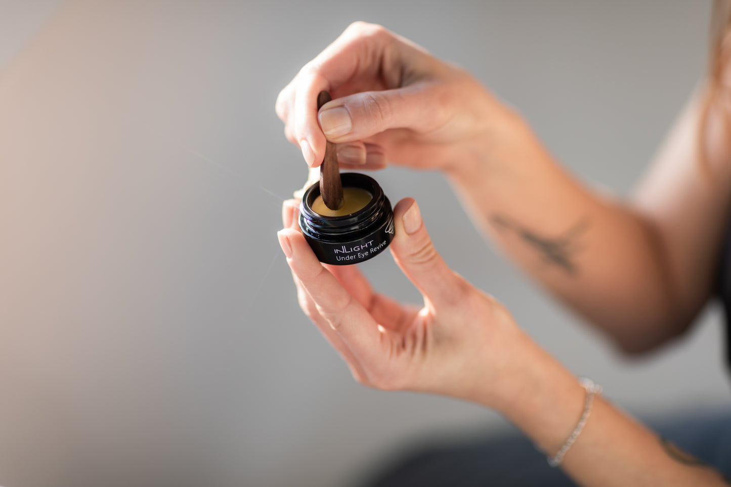 A woman holding a jar of the Inlight Under Eye Revive