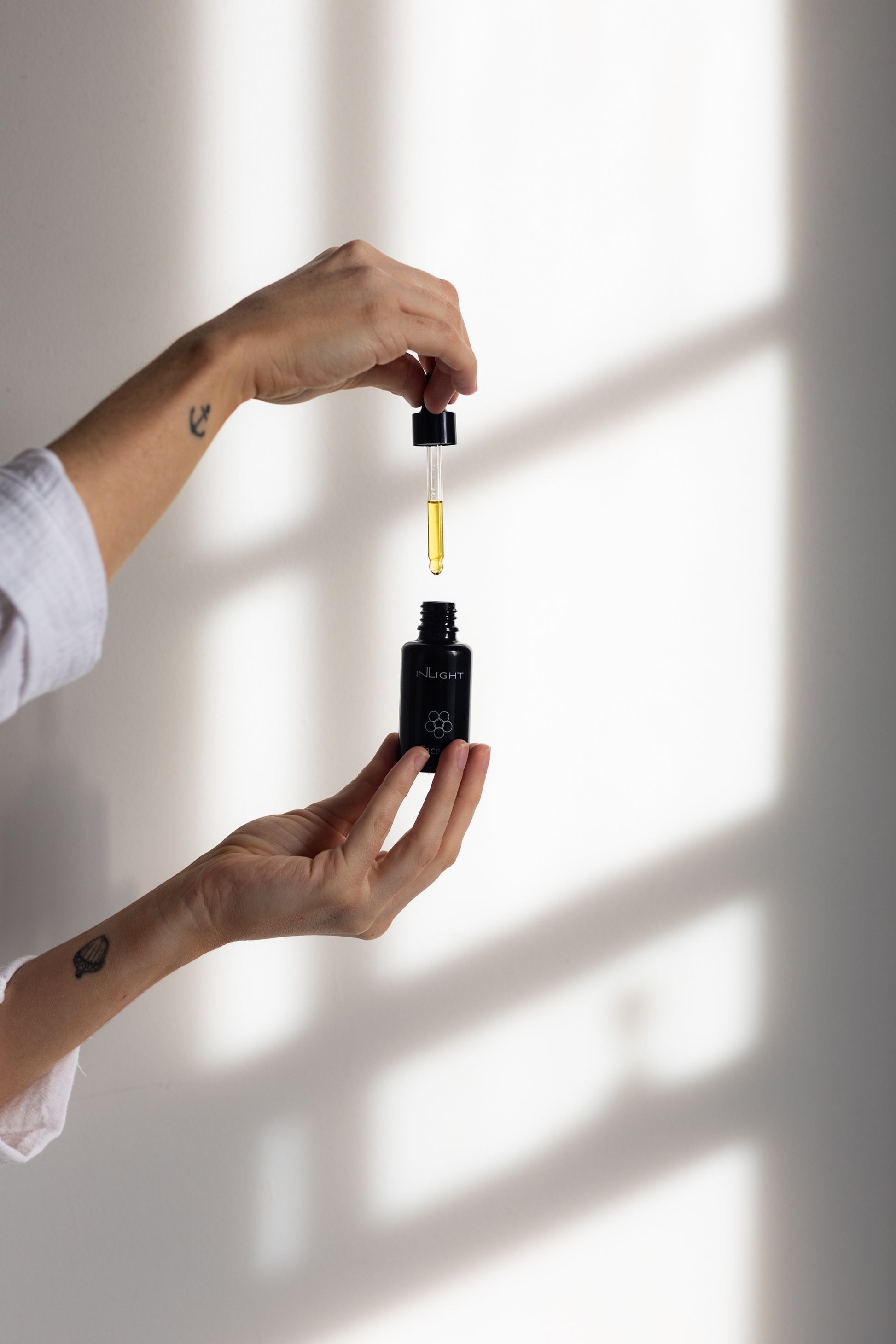 A person holding the Inlight Face Oil bottle 