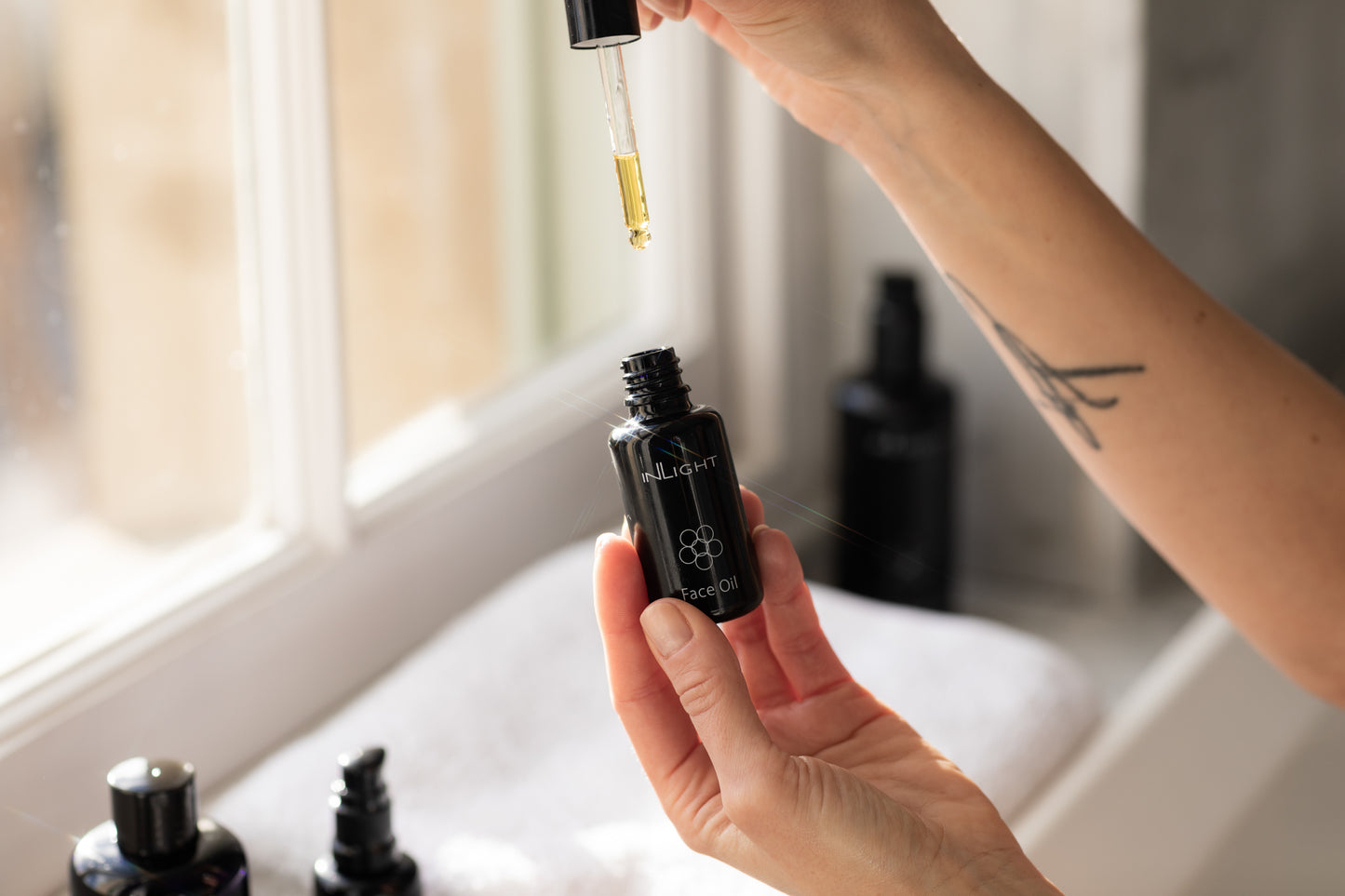 A person holding the Inlight Face Oil bottle 