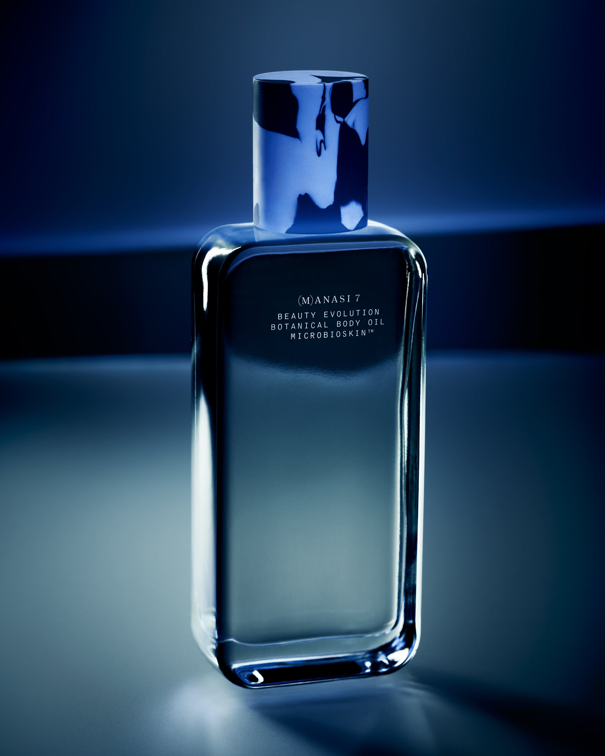 Glass bottle of the Manasi 7 Botanical Body Oil with blue light