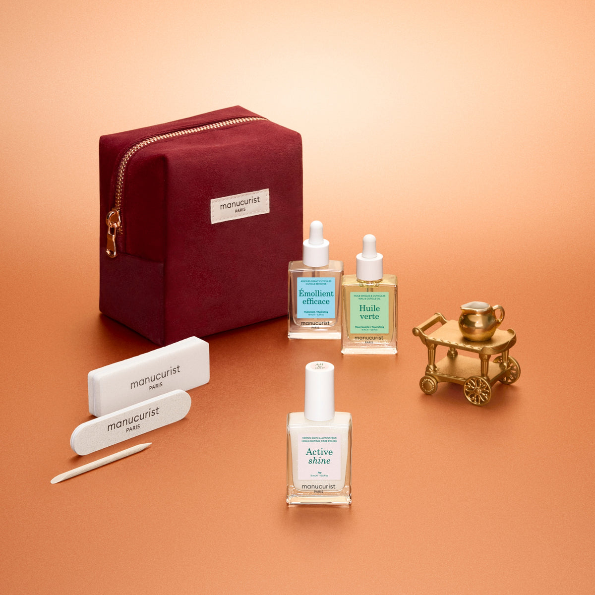 Manucurist Shine Manicure Set with Huile Verte nail oil, Émollient Efficace cuticle remover, Active Shine polish and mini nail files in a burgundy velvet pouch.