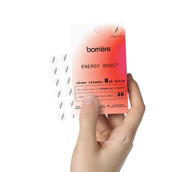Hand holding a 'barriere Energy Boost' vitamin B12 patch with the black bolt symbol packaging against a white background