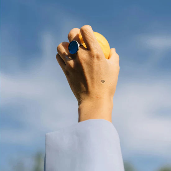 Close-up of a person wearing the Barriere biotin patch with the black diamond symbol on their hand