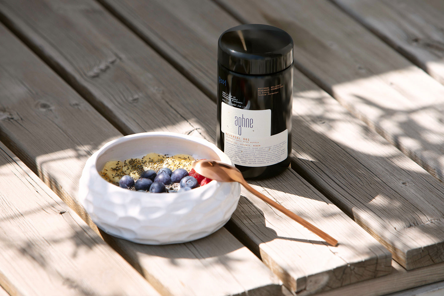 Bowl of granola with blueberries and the container of reversal 001 by aghne on a wooden surface