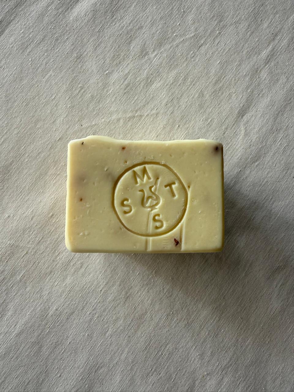 Square bar of lavender soap with the Serendipity Muses logo on a white surface 