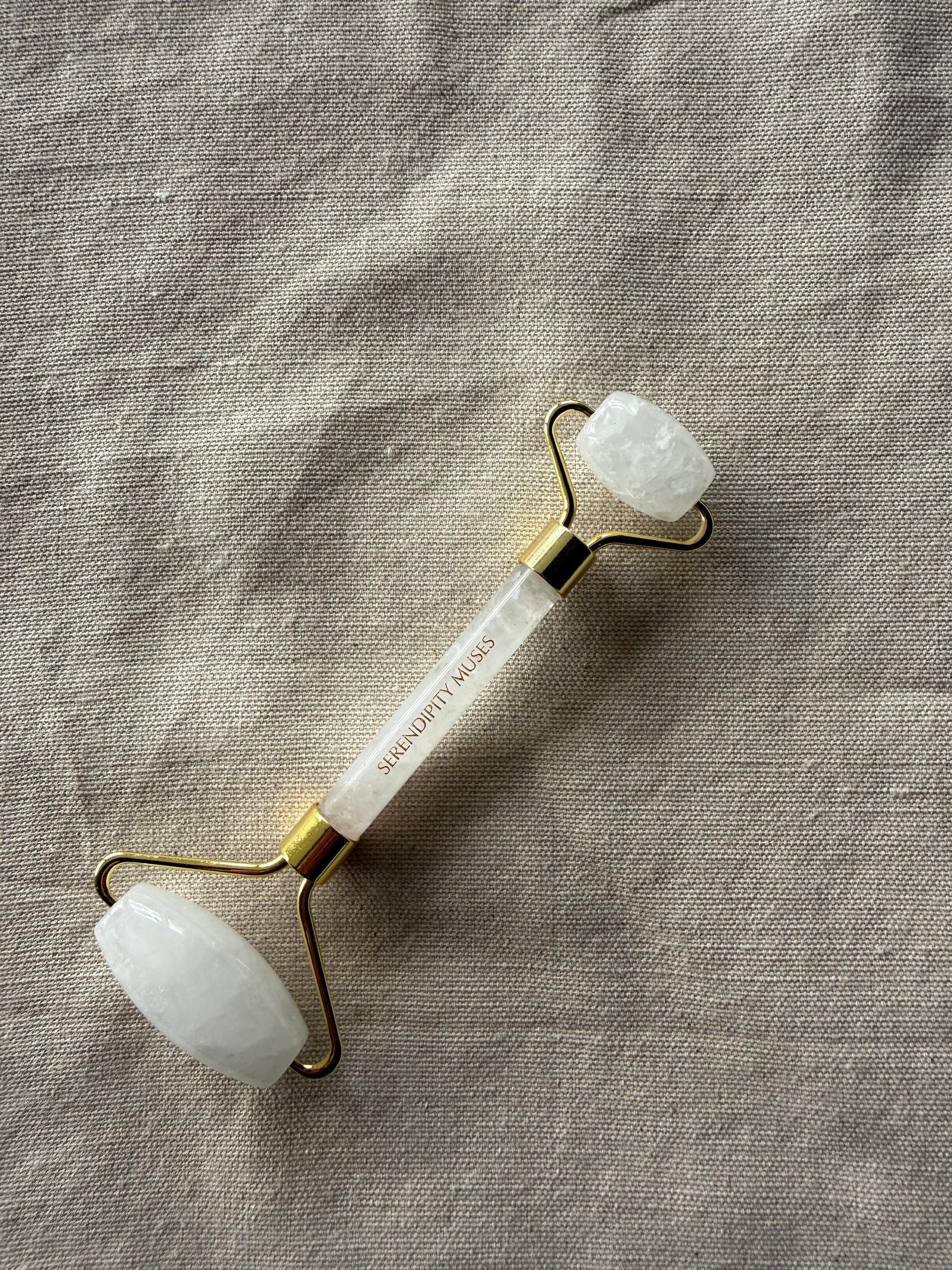 White Jade Facial Roller with gold Serendipity Muses logo on a white background