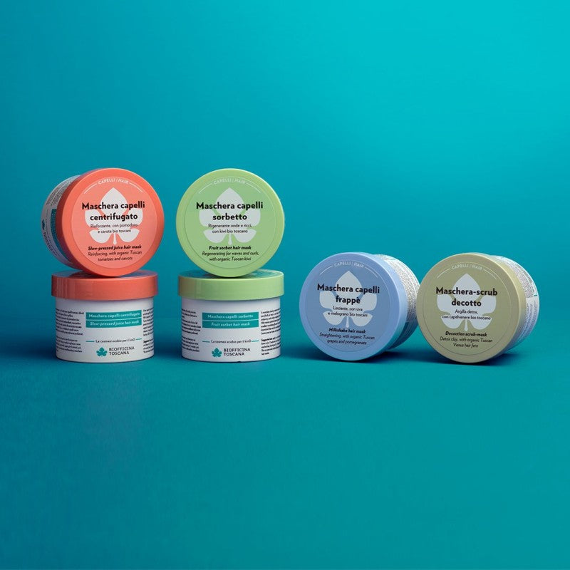 Set of hair mask jars by Biofficina Toscana with colorful lids on a teal background