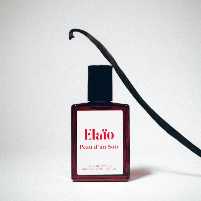 a vanilla leaning against a Perfume bottle labeled 'Elaïo Peau d'un Soir' 