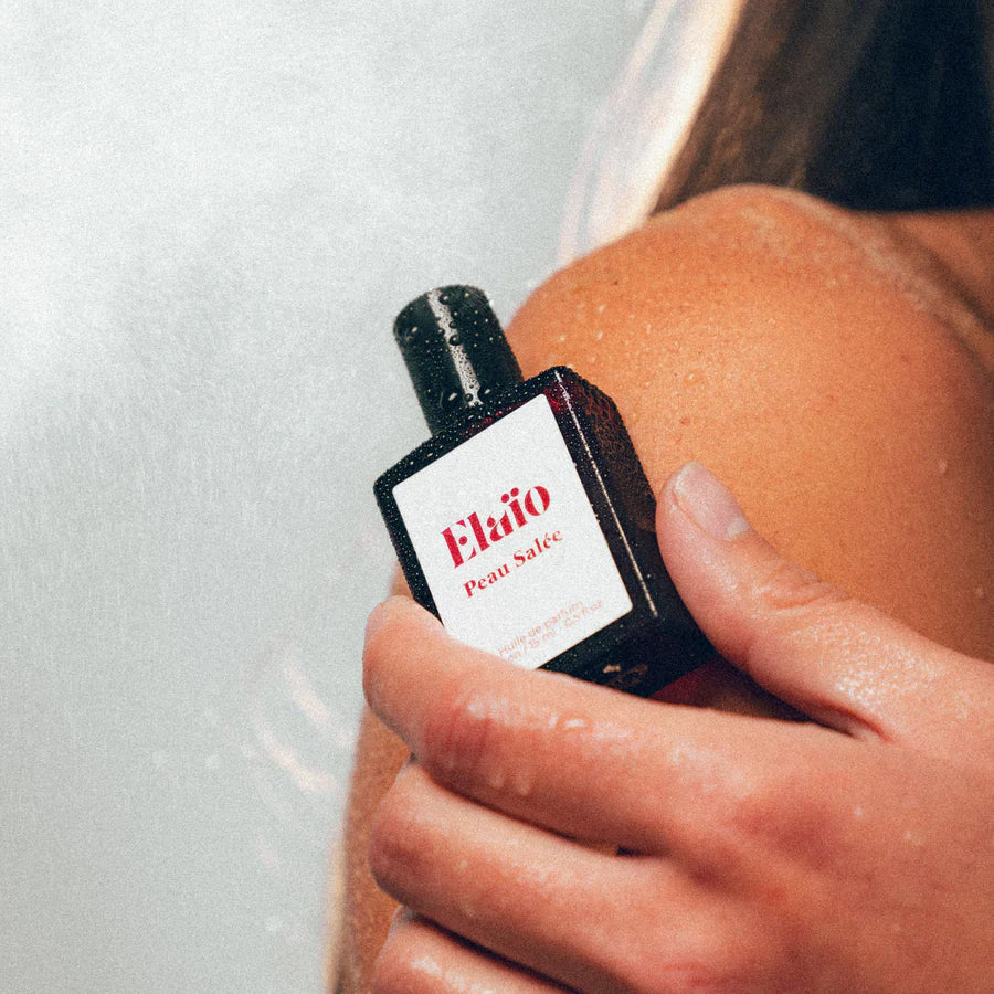 a person holding a Perfume bottle labeled 'Elaïo Peau Salée' 