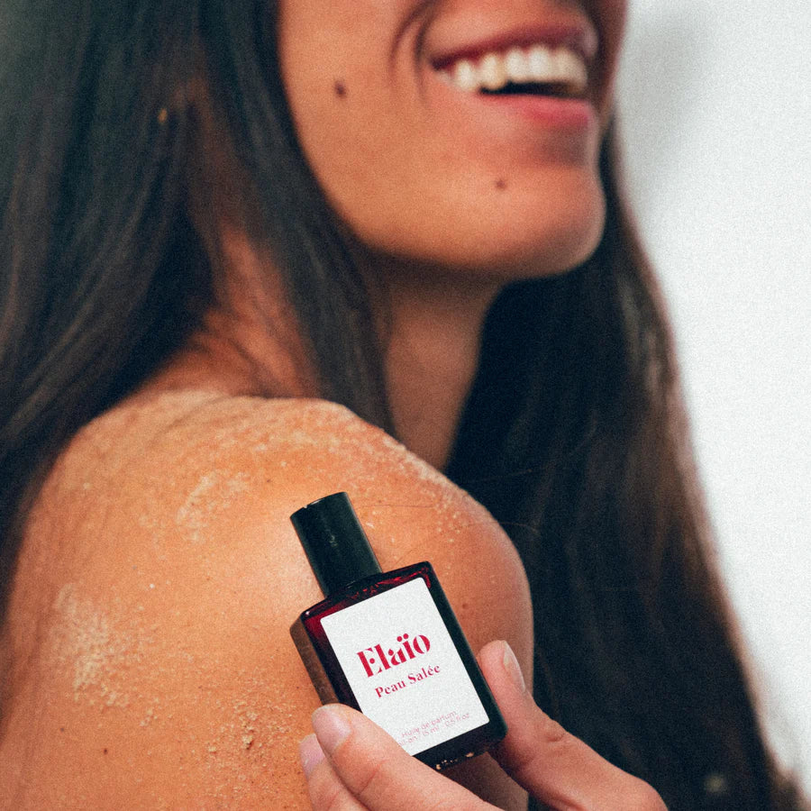 Woman holding a perfume bottle labeled 'Elaïo Peau Salée' 