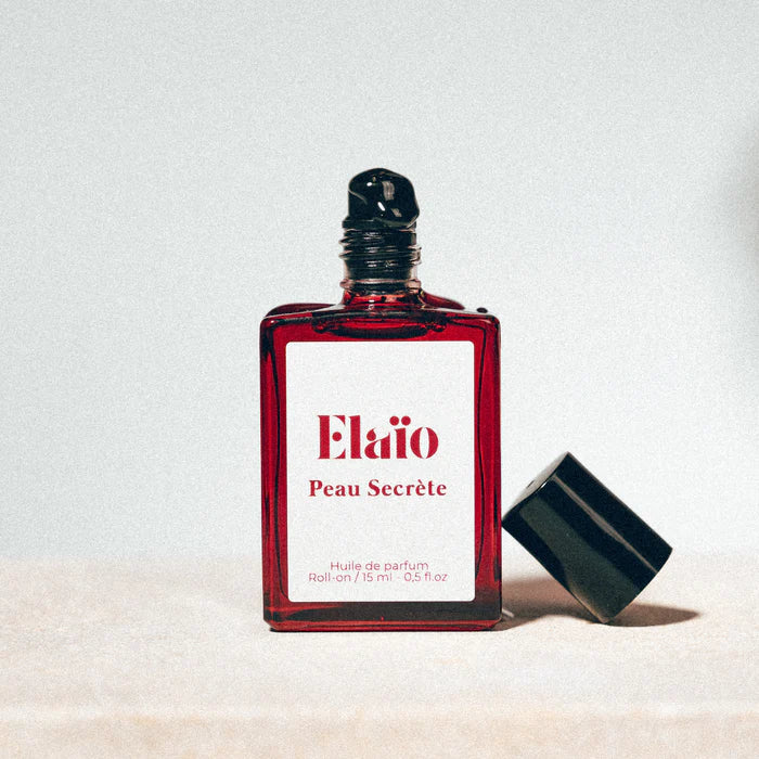 Peau Secrète perfume oil roll-on bottle on a neutral background