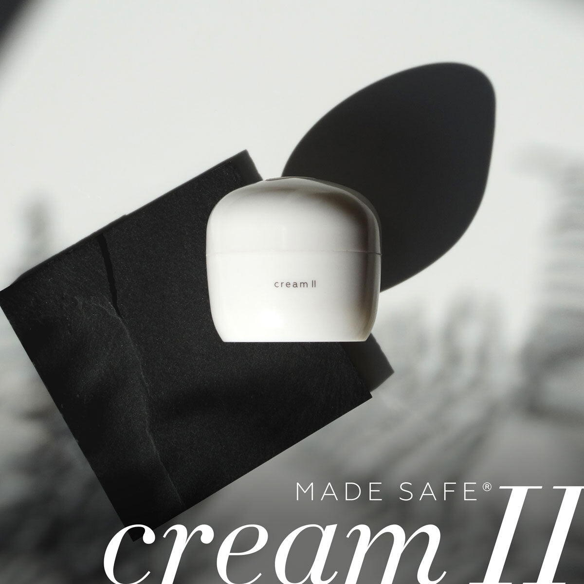 White container labeled 'cream II'  by ayuna on a black cloth with 'Made Safe' branding.