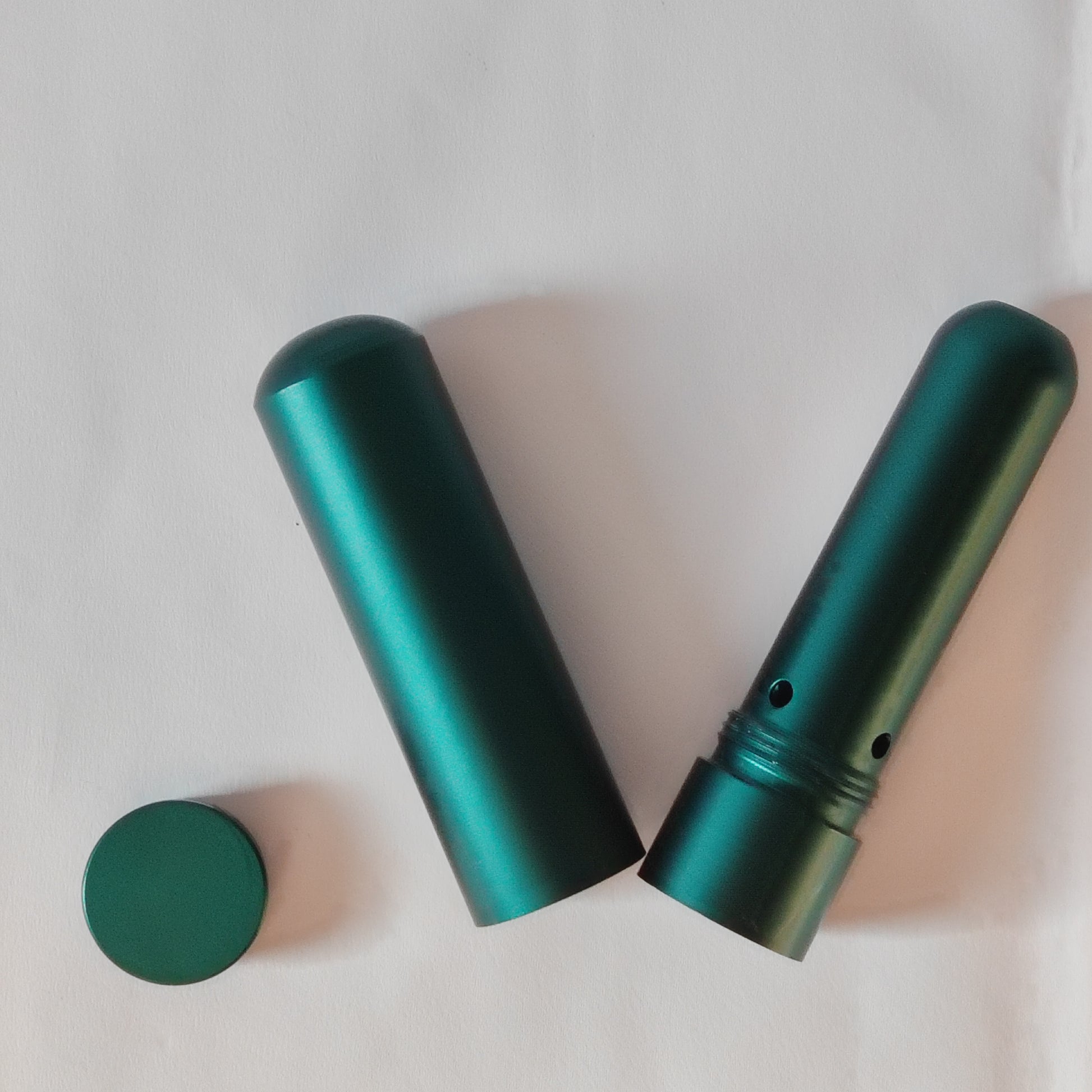 Two green cylindrical nasal inhalers on a light gray background