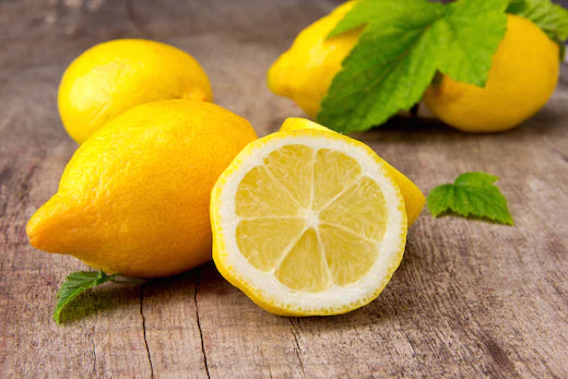 Fresh lemons with one cut in half on a wooden surface