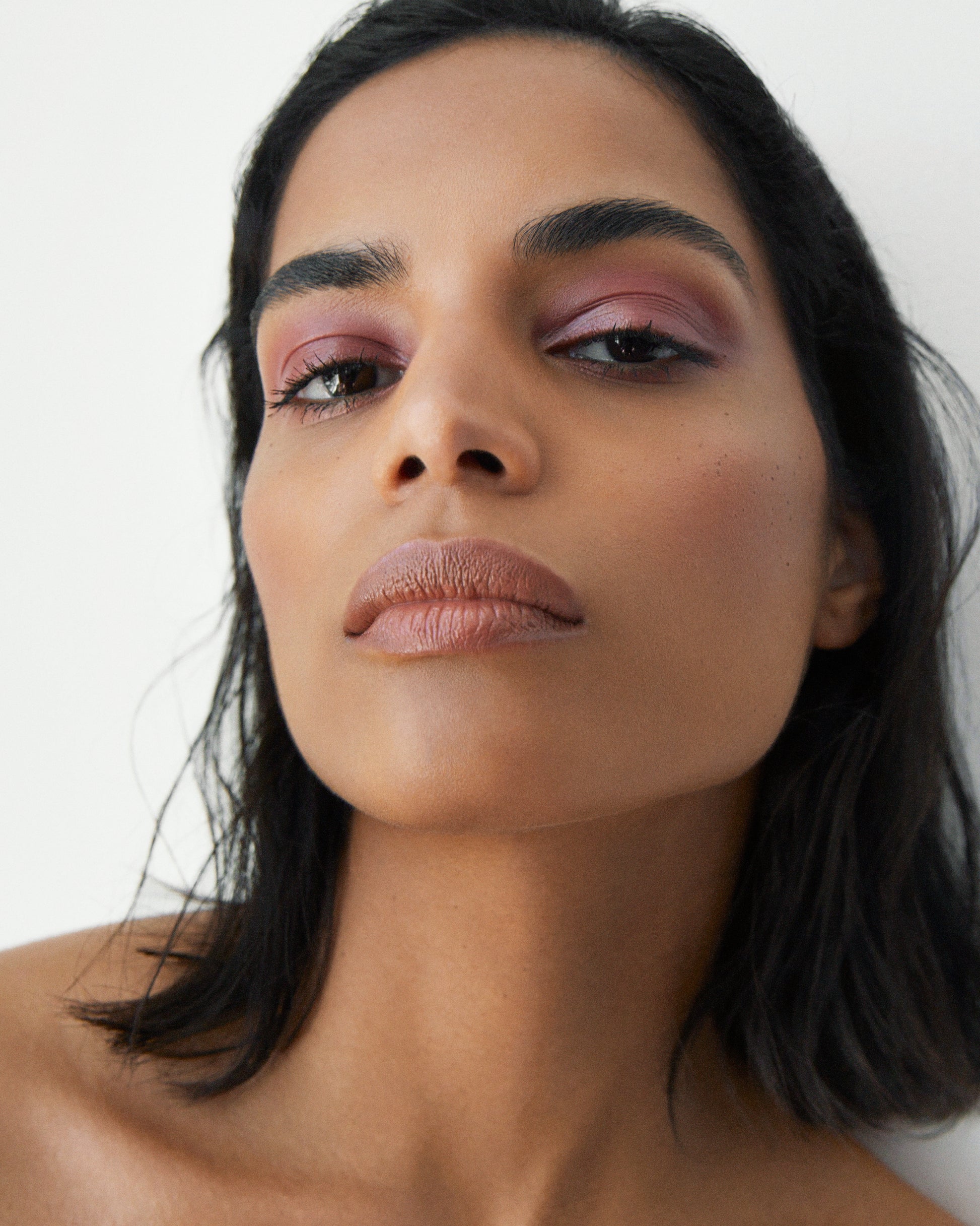 Close-up of a woman wearing the Manasi 7 Dianthus All over Colour on her eyes, lips and cheeks with a neutral background