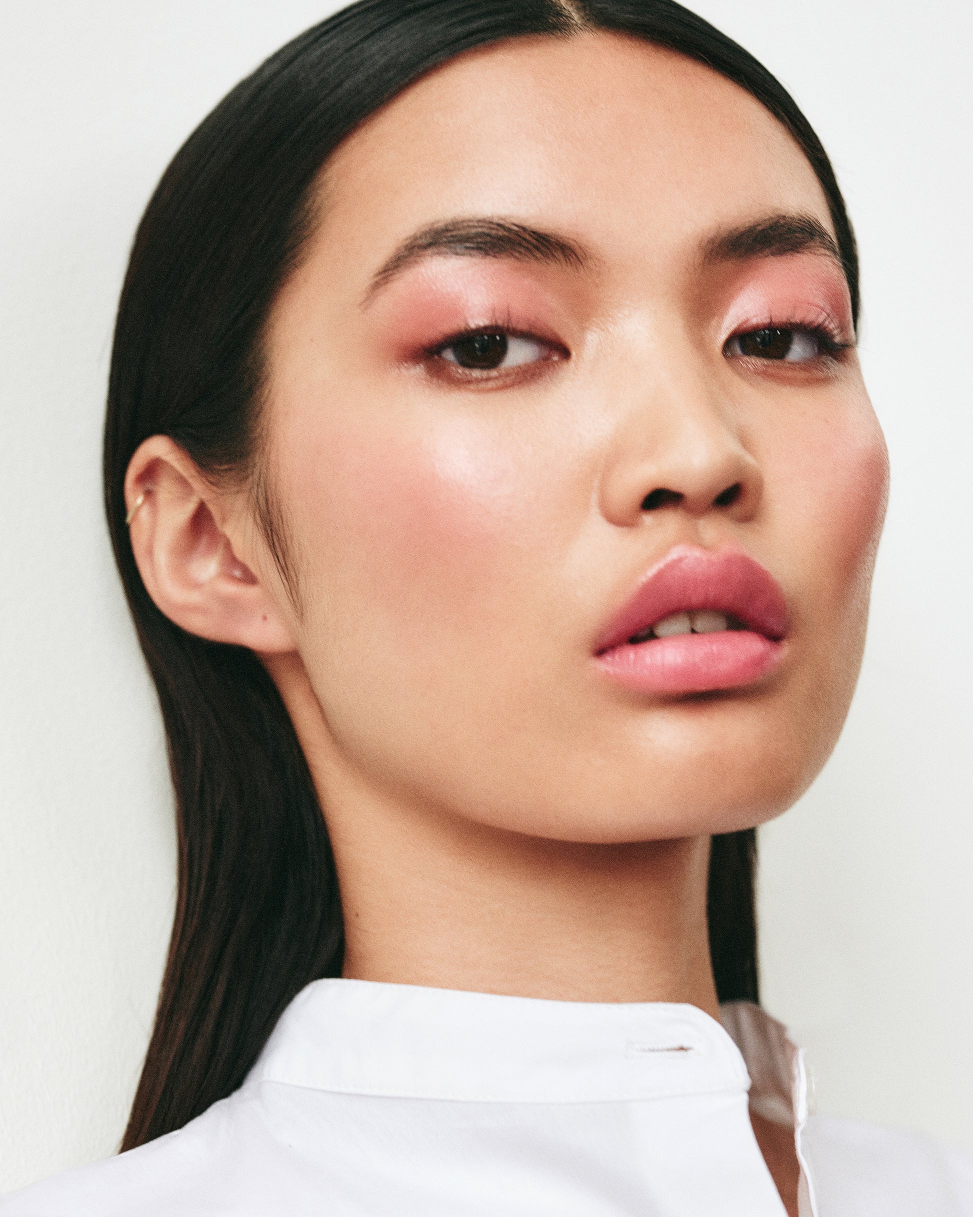 Close-up of a woman wearing the Manasi 7 Etruscan All over Colour on her eyes, lips and cheeks with a neutral background