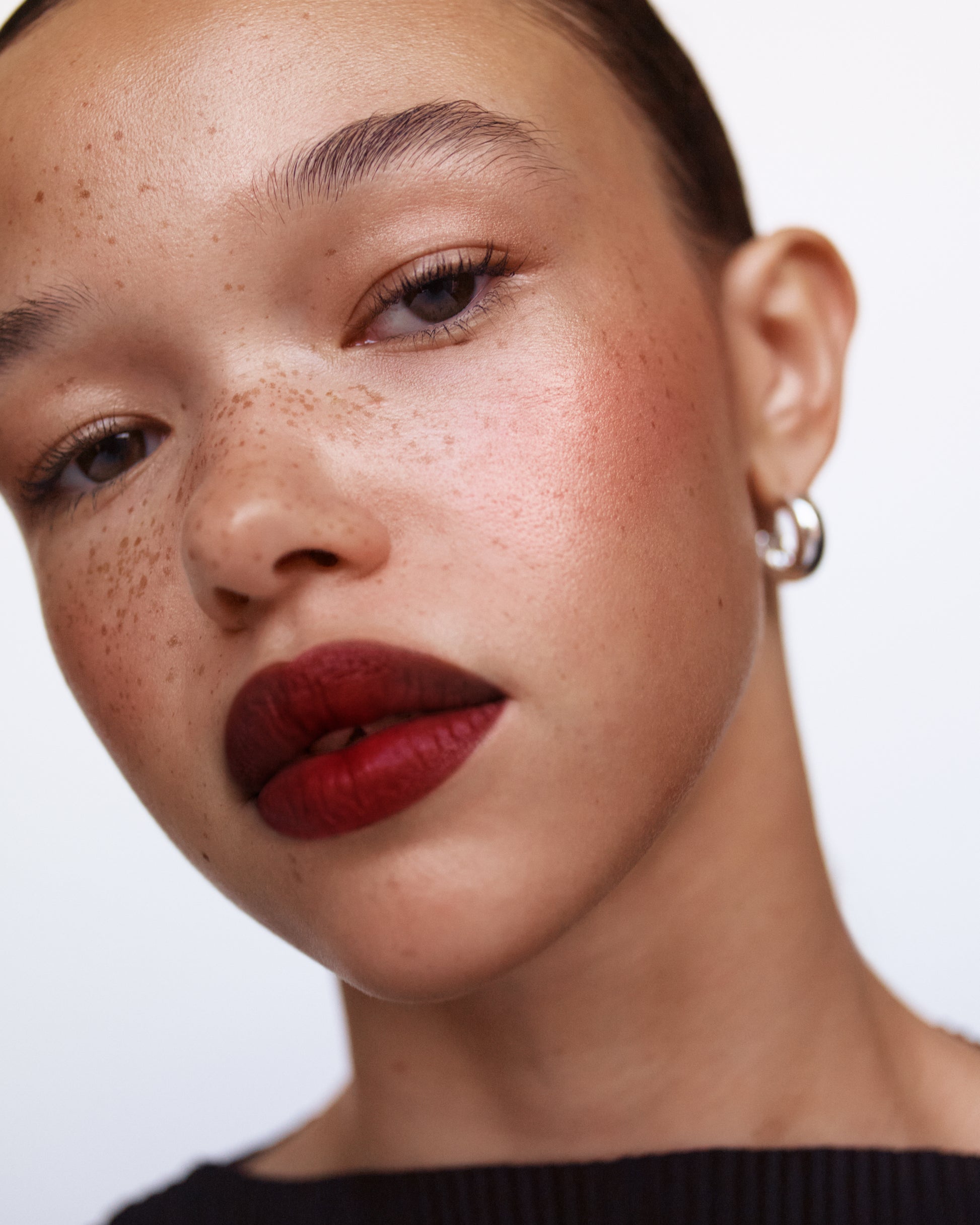 Close-up of a woman wearing the Manasi 7 Pacaya All over Colour on her eyes, lips and cheeks with a neutral background