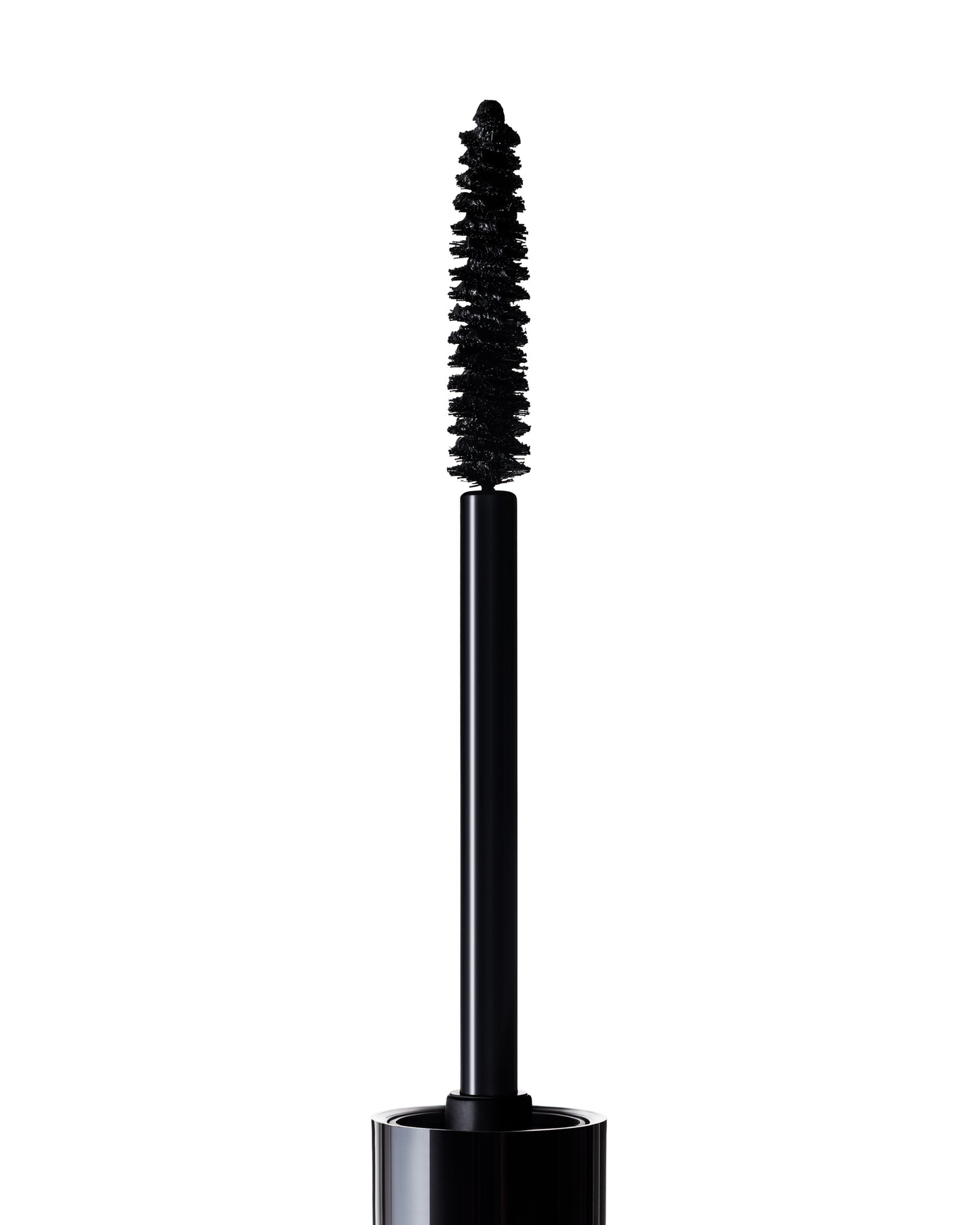 A close-up of an open Manasi 7 Precision Mascara showing the black mascara wand with a bristled brush coated in product, set against a white background.