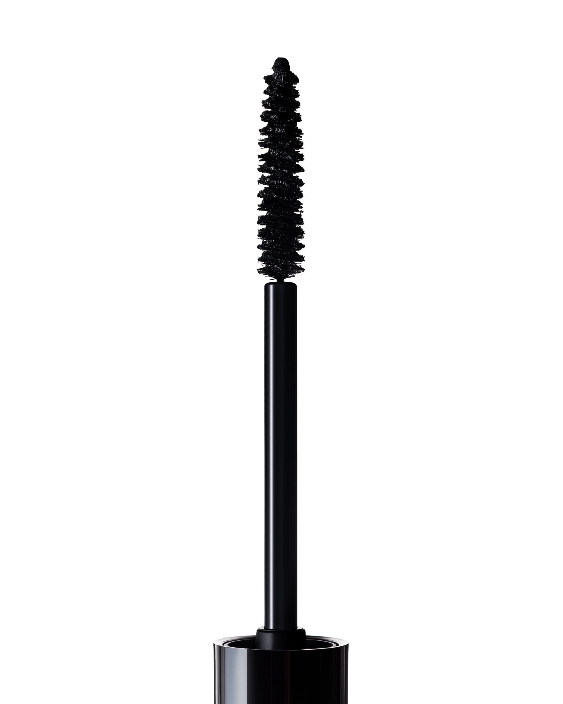A close-up of an open Manasi 7 Precision Mascara showing the black mascara wand with a bristled brush coated in product, set against a white background.