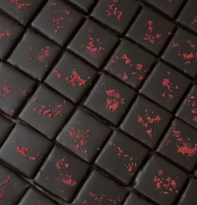 Dark chocolate with red berry pieces on a grid pattern