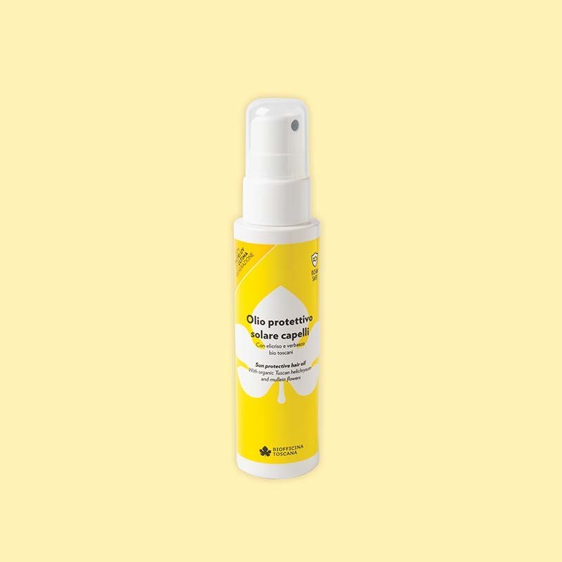 Spray bottle of sun protective hair oil by biofficina toscana with yellow label on a light yellow background