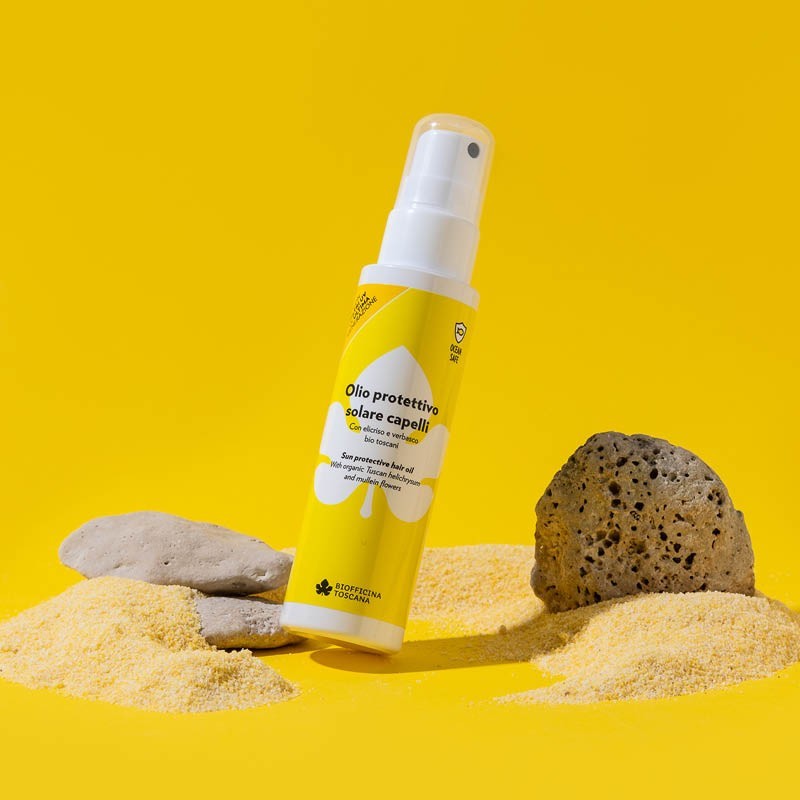 Yellow bottle with white spray nozzle of the sun protective oil by biofficina toscana on a yellow background