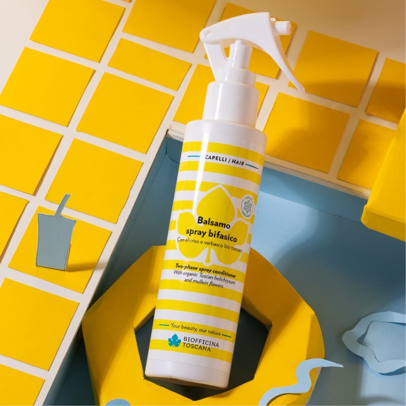 Yellow and white bottle of two phase spray conditioner by biofficina toscana on a yellow and blue background