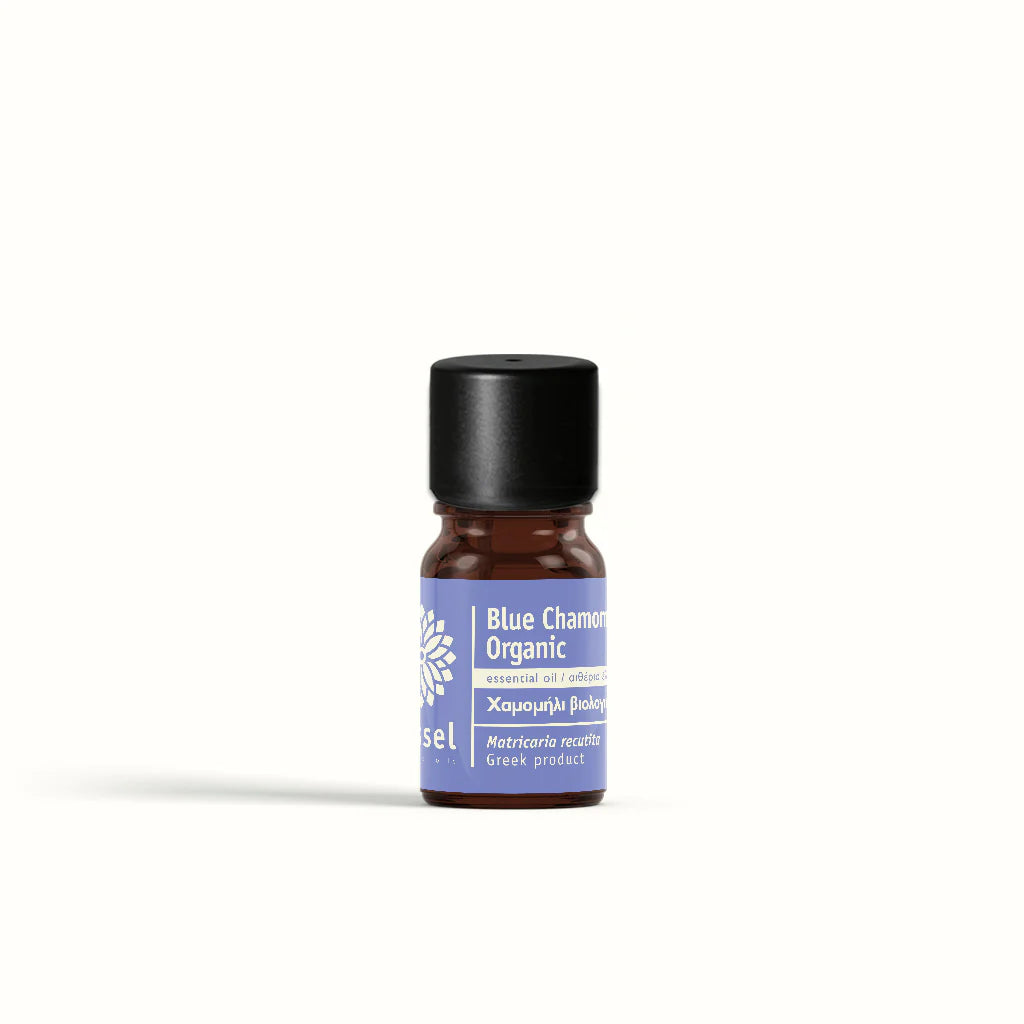 Small bottle of Blue Chamomile Organic essential oil by vessel on a white background