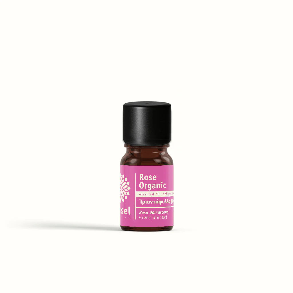 Bottle of rose organic essential oil by vessel with a pink label on a white background