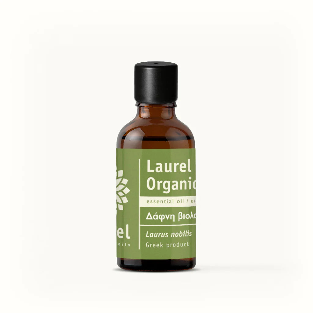 Bottle of Laurel Organic essential oil by vessel with a green label on a white background